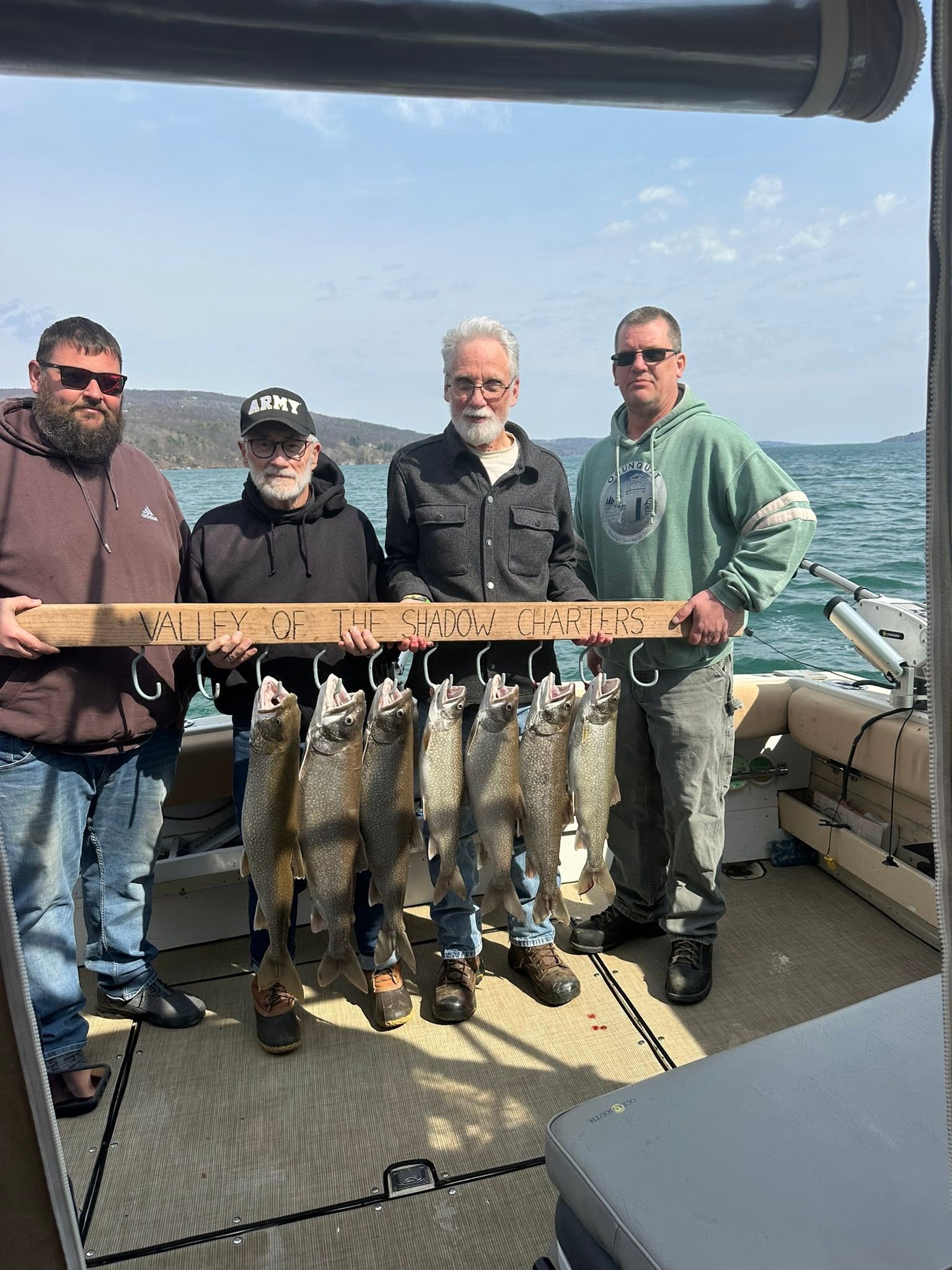 Four anglers displaying their catch of lake trout on a charter boat in South Bristol NY