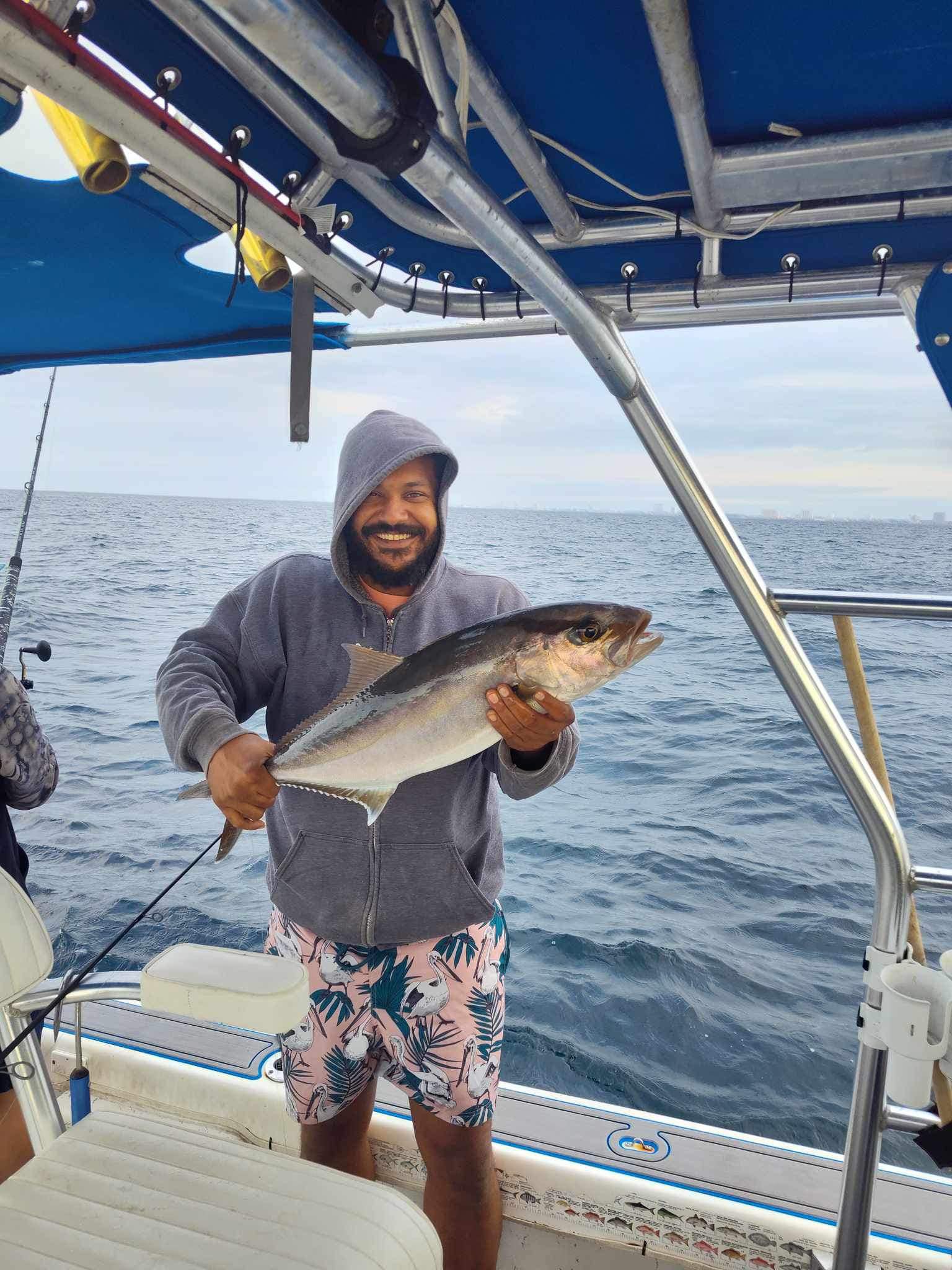 Angler holding freshly caught Greater Amberjack on fishing boat deck