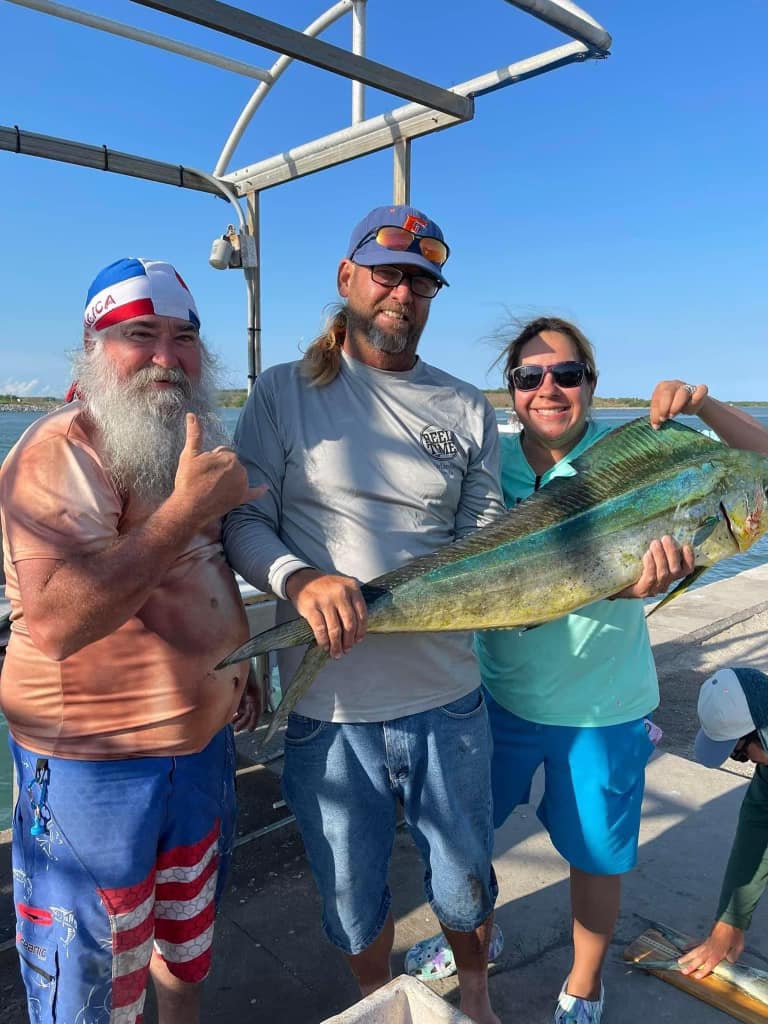 Three people on fishing boat holding large mahi mahi catch