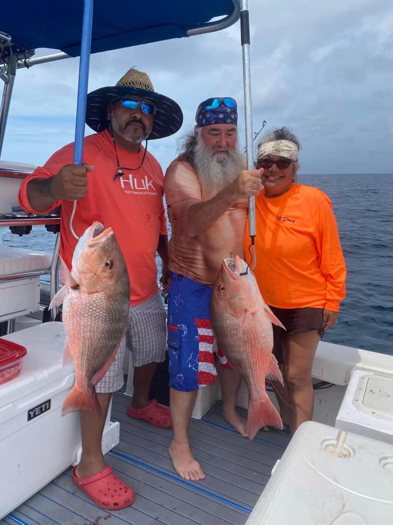 Two red snapper fish displayed on fishing boat deck after successful catch