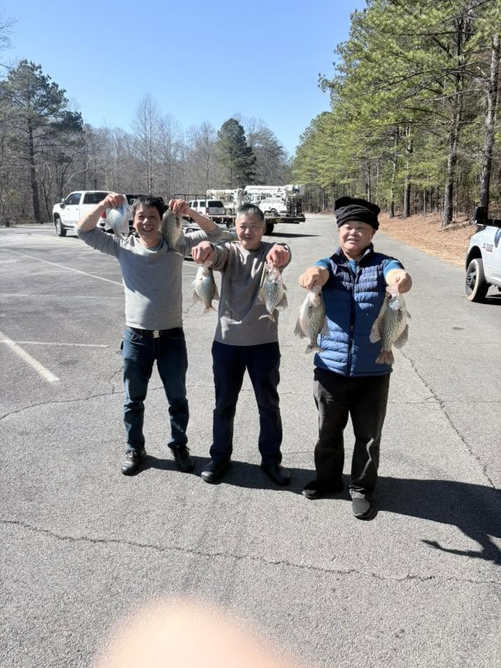 Three anglers displaying freshly caught crappie and other fish in Cumming GA parking area