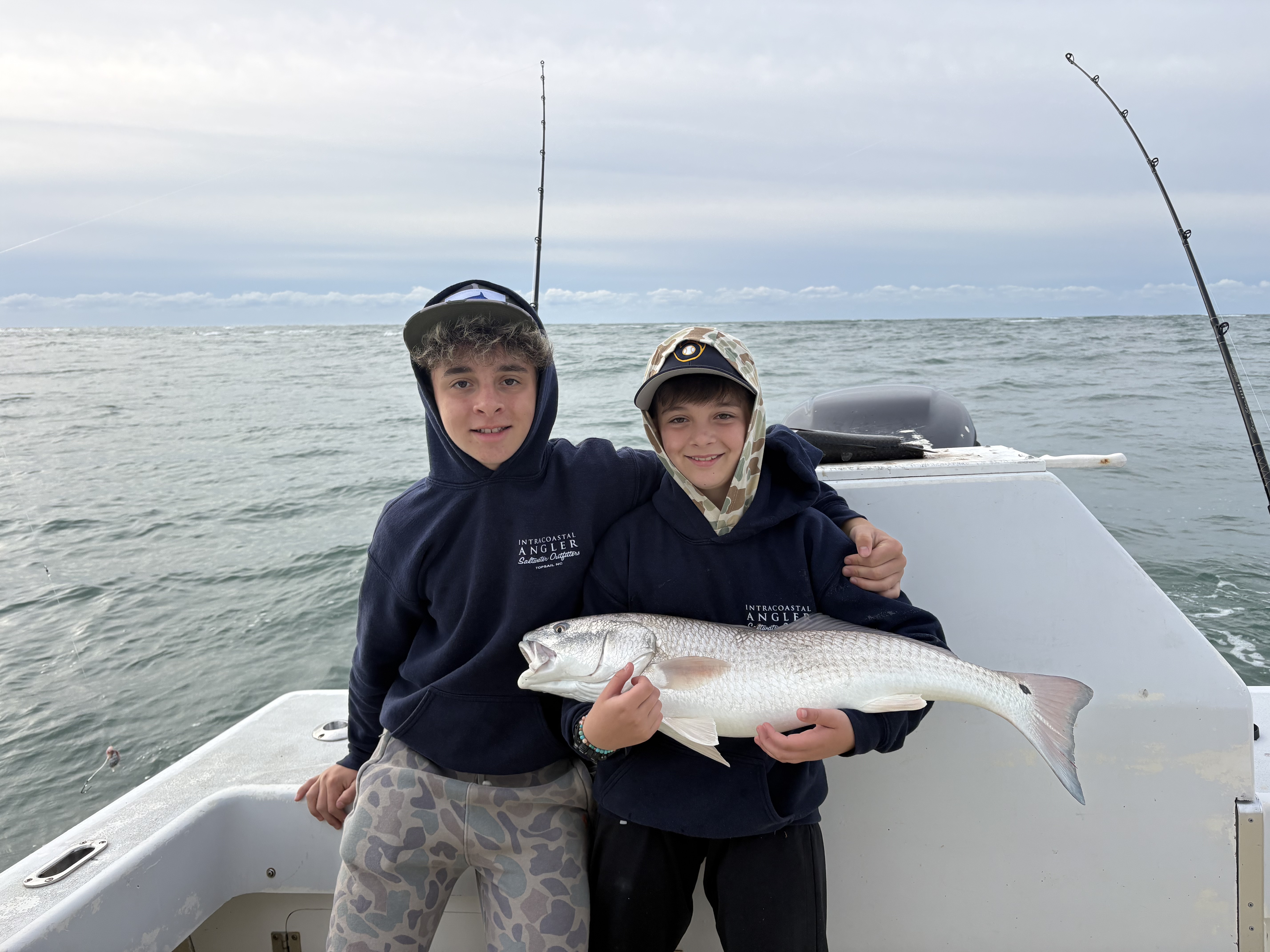 Two young anglers displaying a caught redfish on fishing boat in Ocracoke NC waters