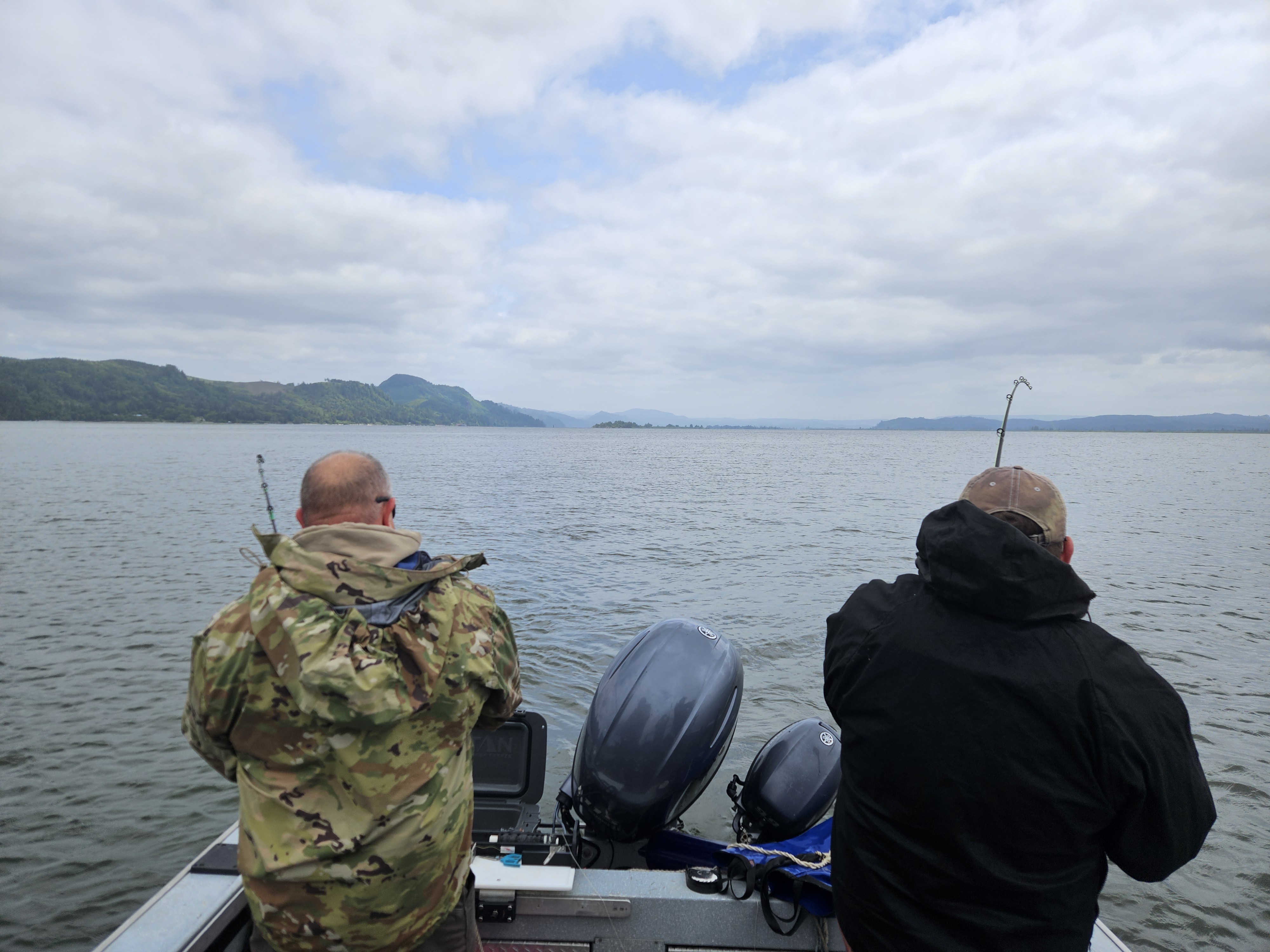 Two anglers fishing from boat on large lake with mountains in background near Astoria OR