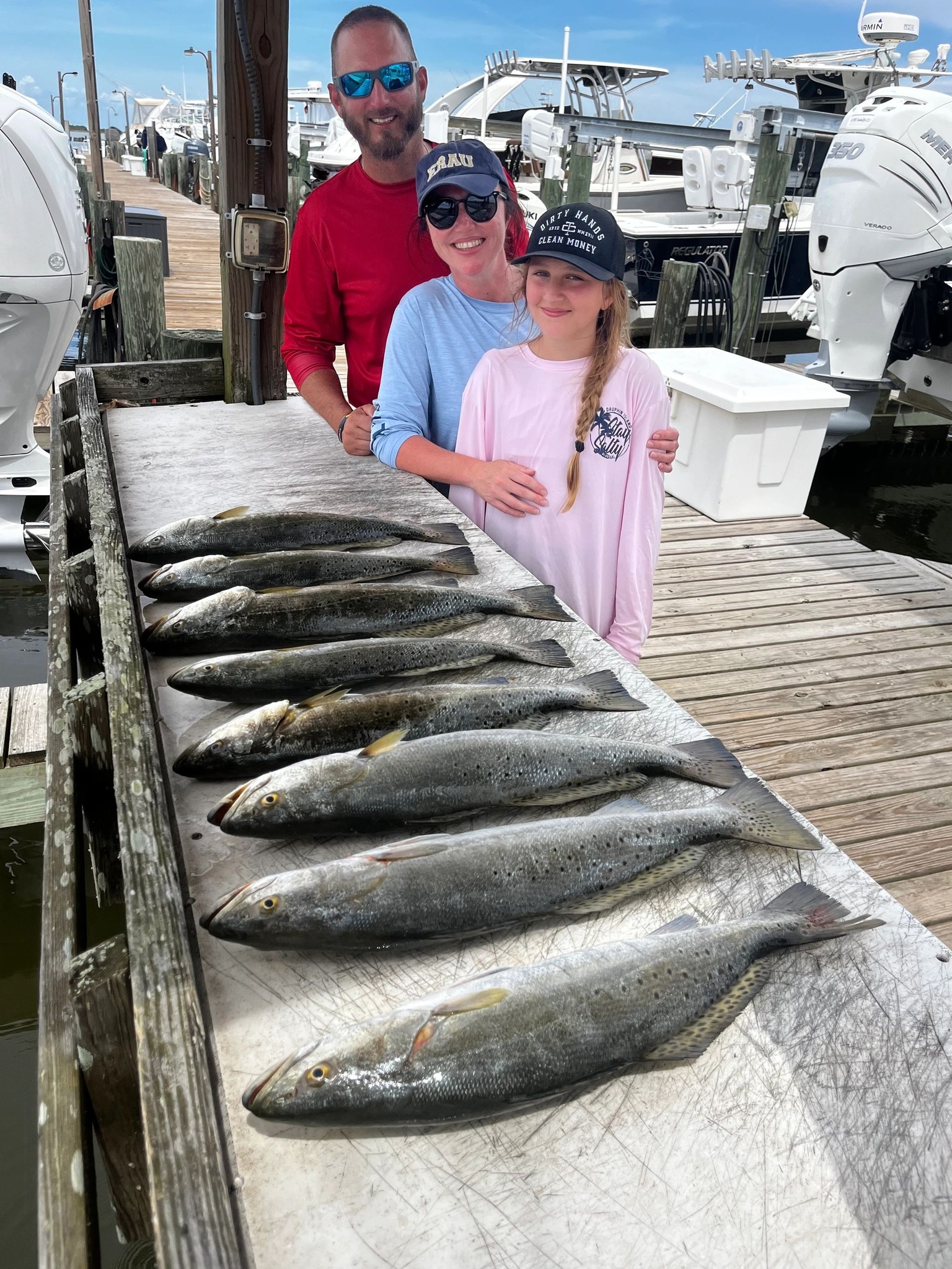 Successful speckled trout fishing trip at Dauphin Island AL with multiple fish displayed on marina dock