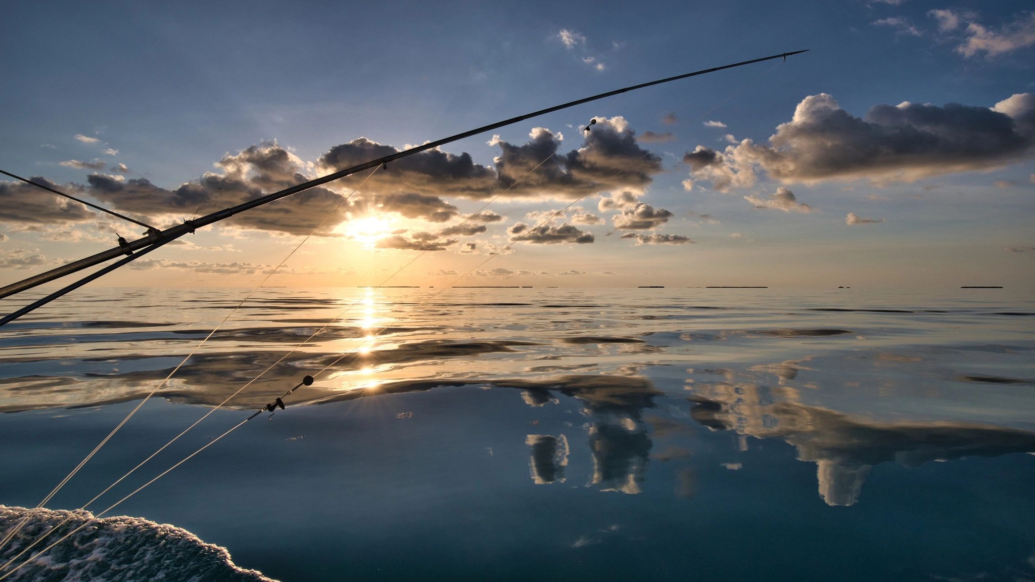 Fishing boat rigging and lines silhouetted against sunset over calm waters near Dauphin Island Alabama