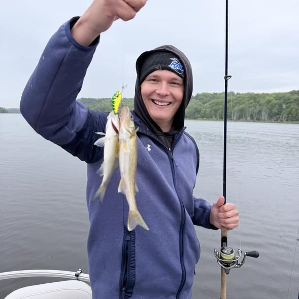 Walleye catch displayed on fishing boat in Stillwater MN with fishing rod and lake background
