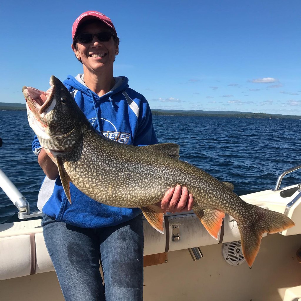A solo angler holds a large lake trout in Marquette