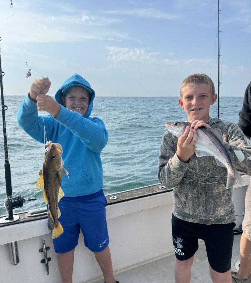 Two young anglers displaying their fresh Atlantic Cod catch on fishing boat in Gloucester MA waters