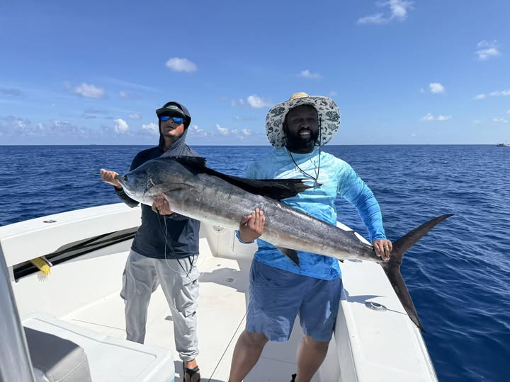 Two anglers holding large fish catch on fishing boat in Riviera Beach FL waters