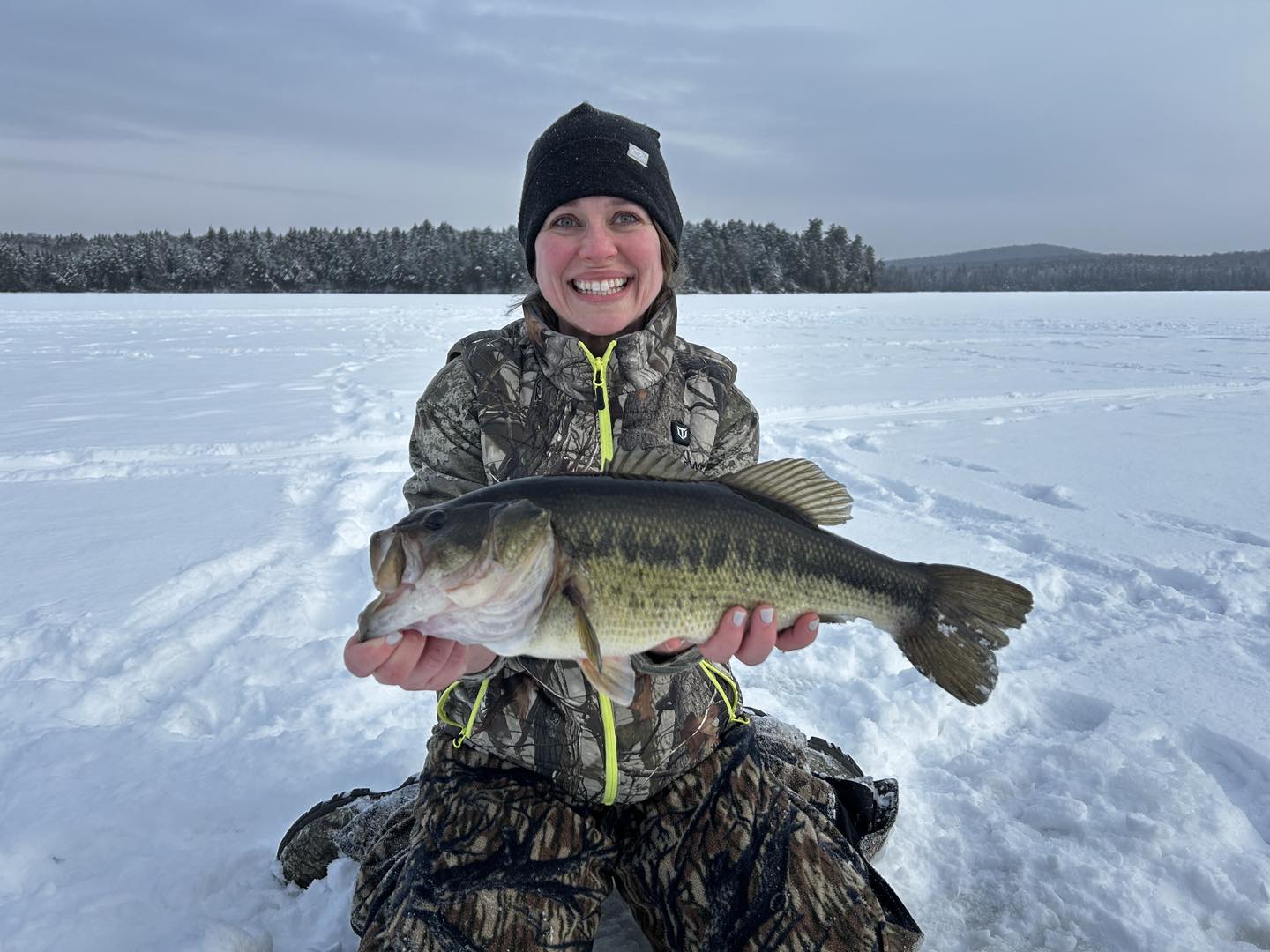 Ice fishing catch displaying largemouth bass on frozen lake in Paul Smiths NY