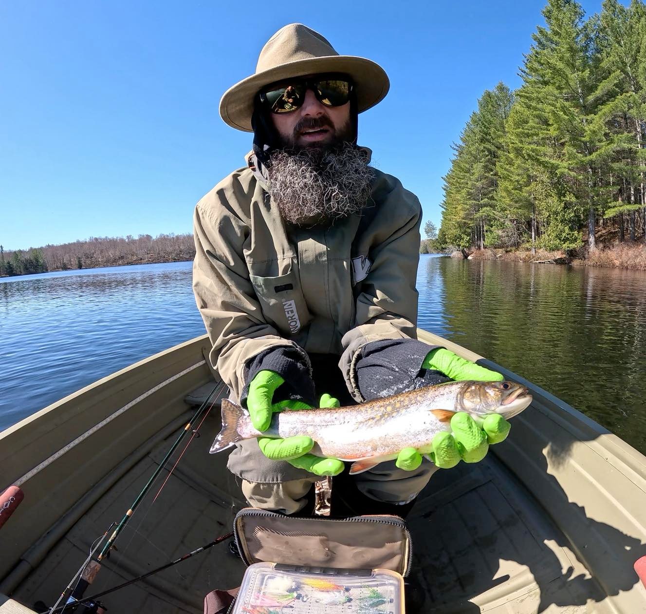 Angler holding caught fish in boat on lake in Paul Smiths NY