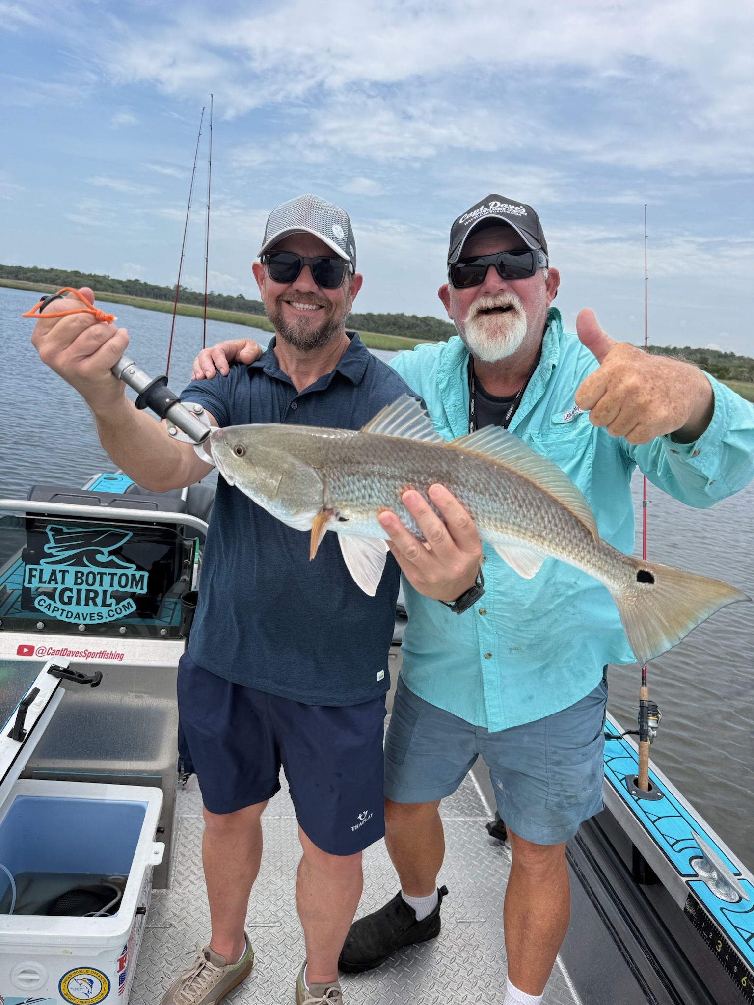 Two anglers displaying a caught redfish on fishing boat in Jacksonville FL waters