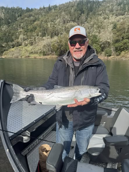 Angler holding large salmon on fishing boat in Myrtle Creek OR