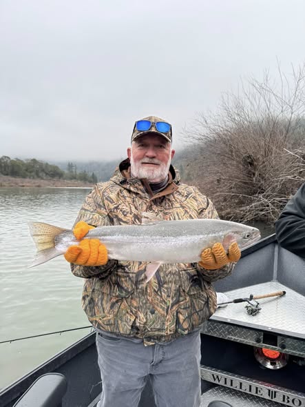 Angler holding large steelhead fish on boat in Myrtle Creek OR