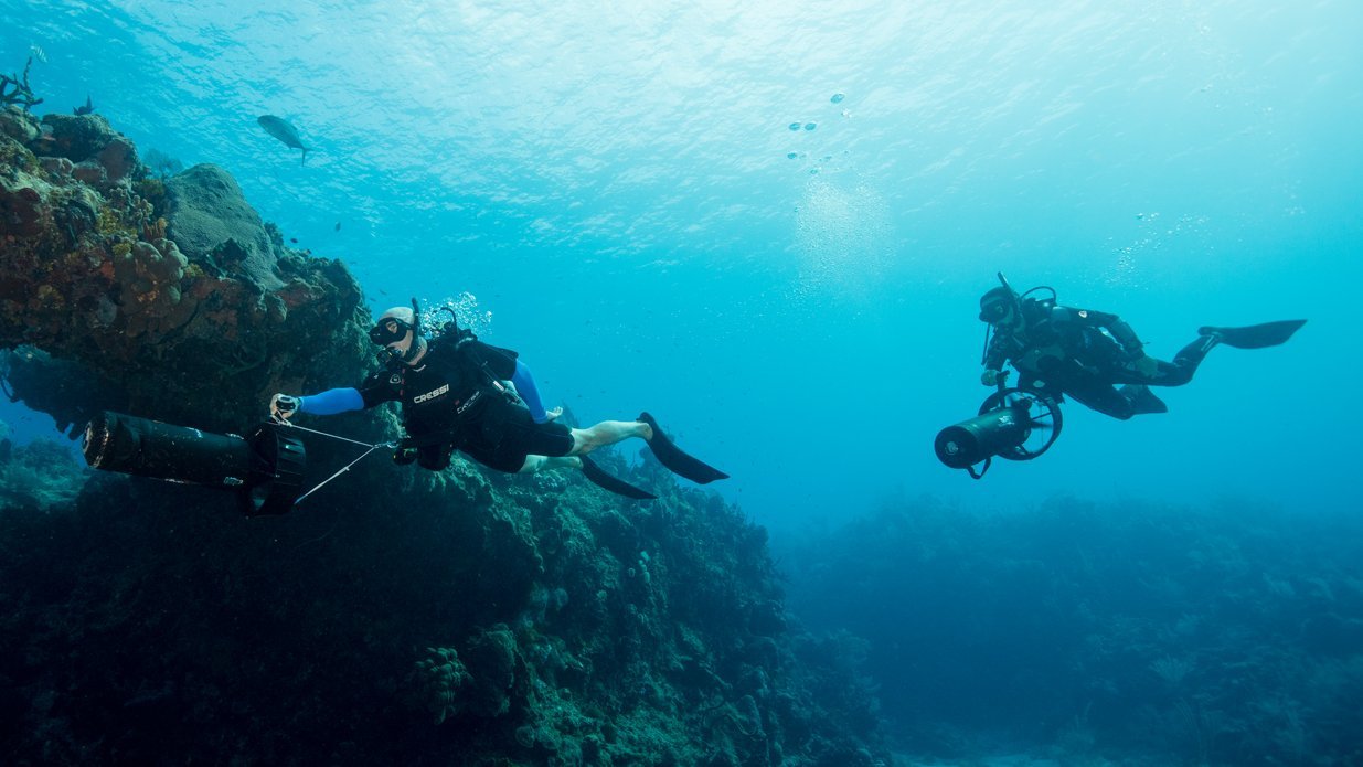 Diver using underwater scooter DPV propulsion vehicle while scuba diving eLearning course