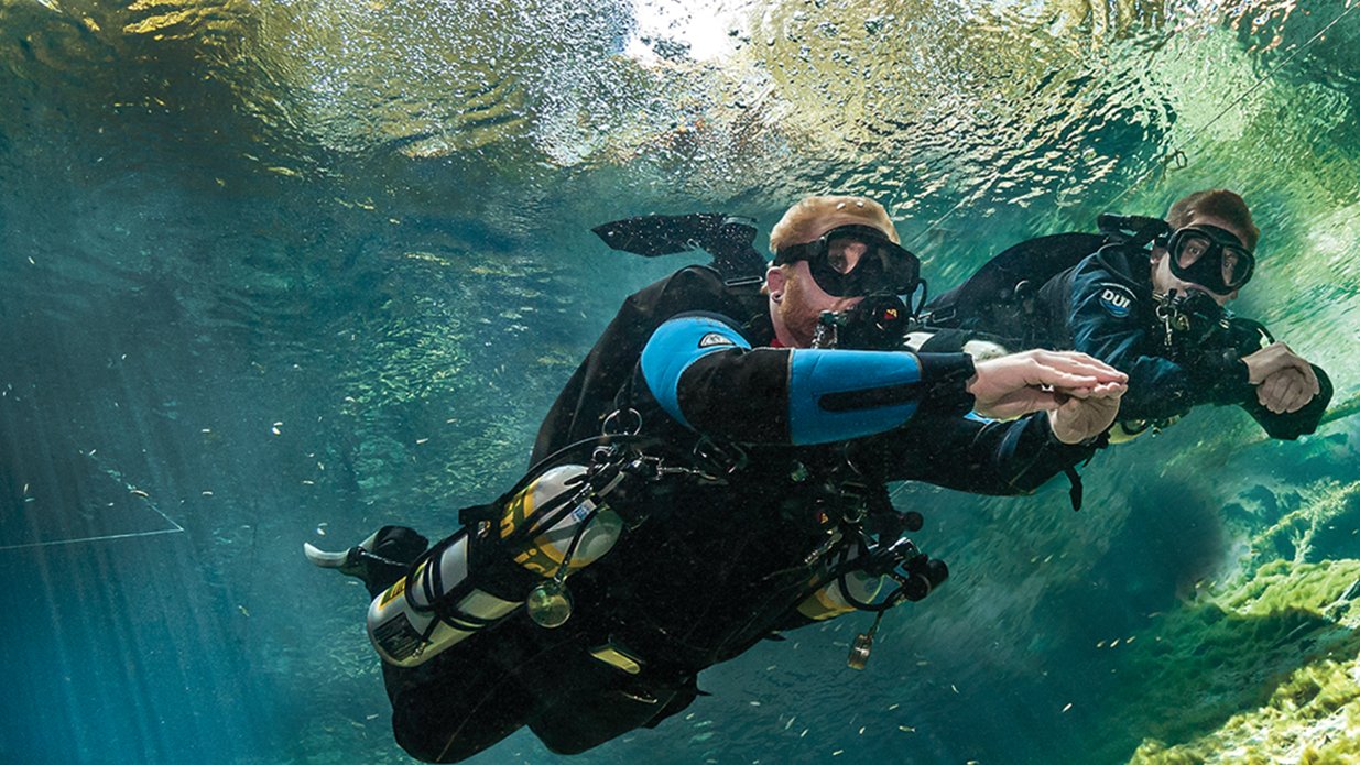 PADI sidemount scuba diver with tanks positioned at sides for balanced underwater diving
