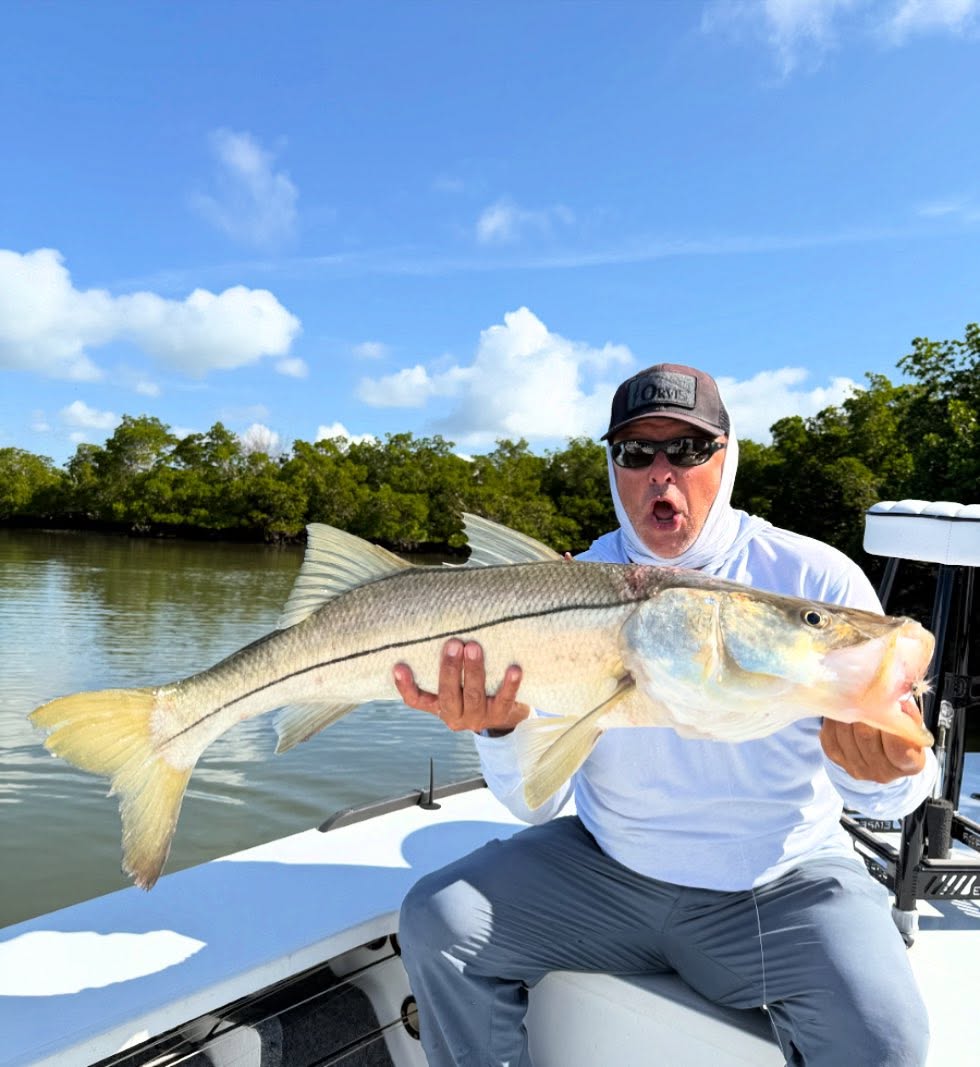 Angler holding large snook fish on boat in Naples FL waters