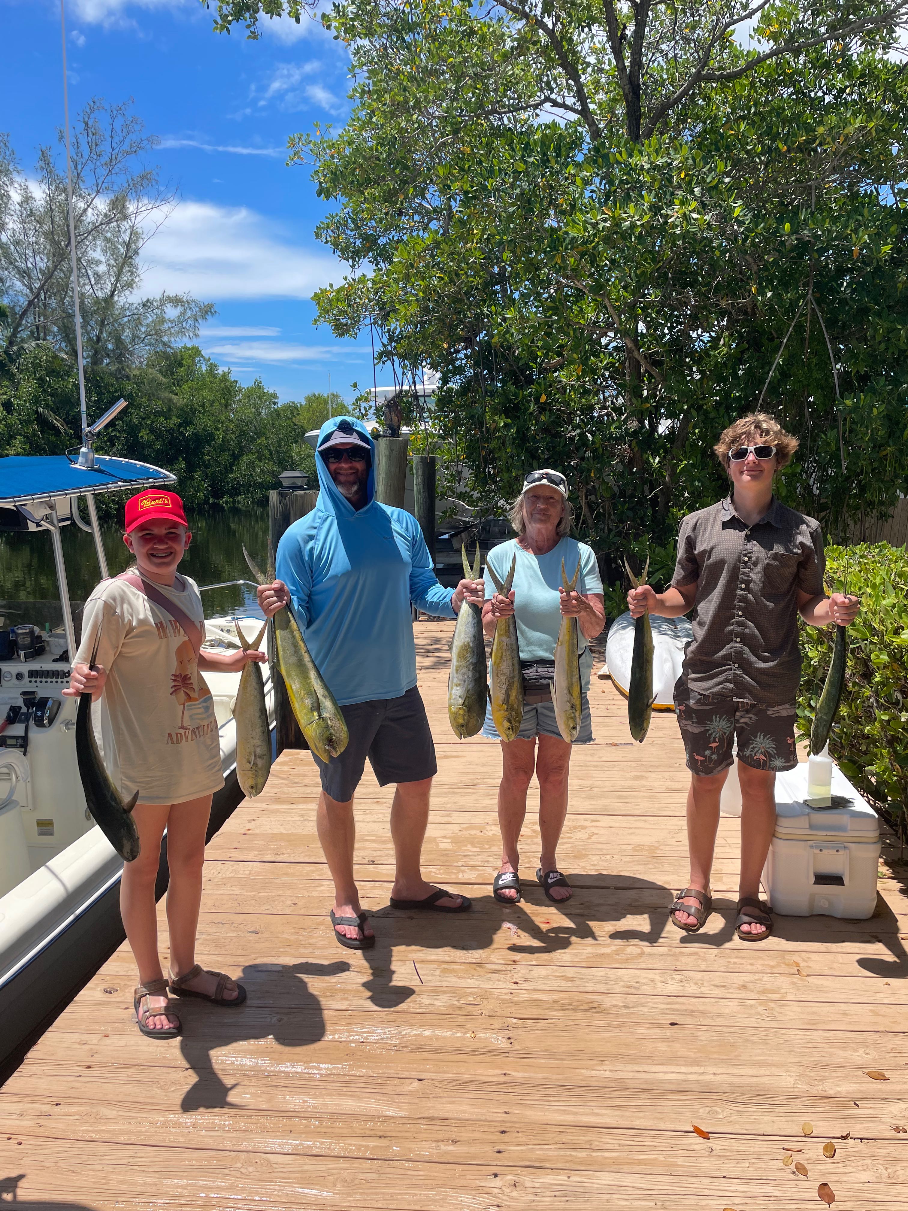 Four anglers displaying fresh caught mahi mahi fish on wooden dock in Key Largo Florida