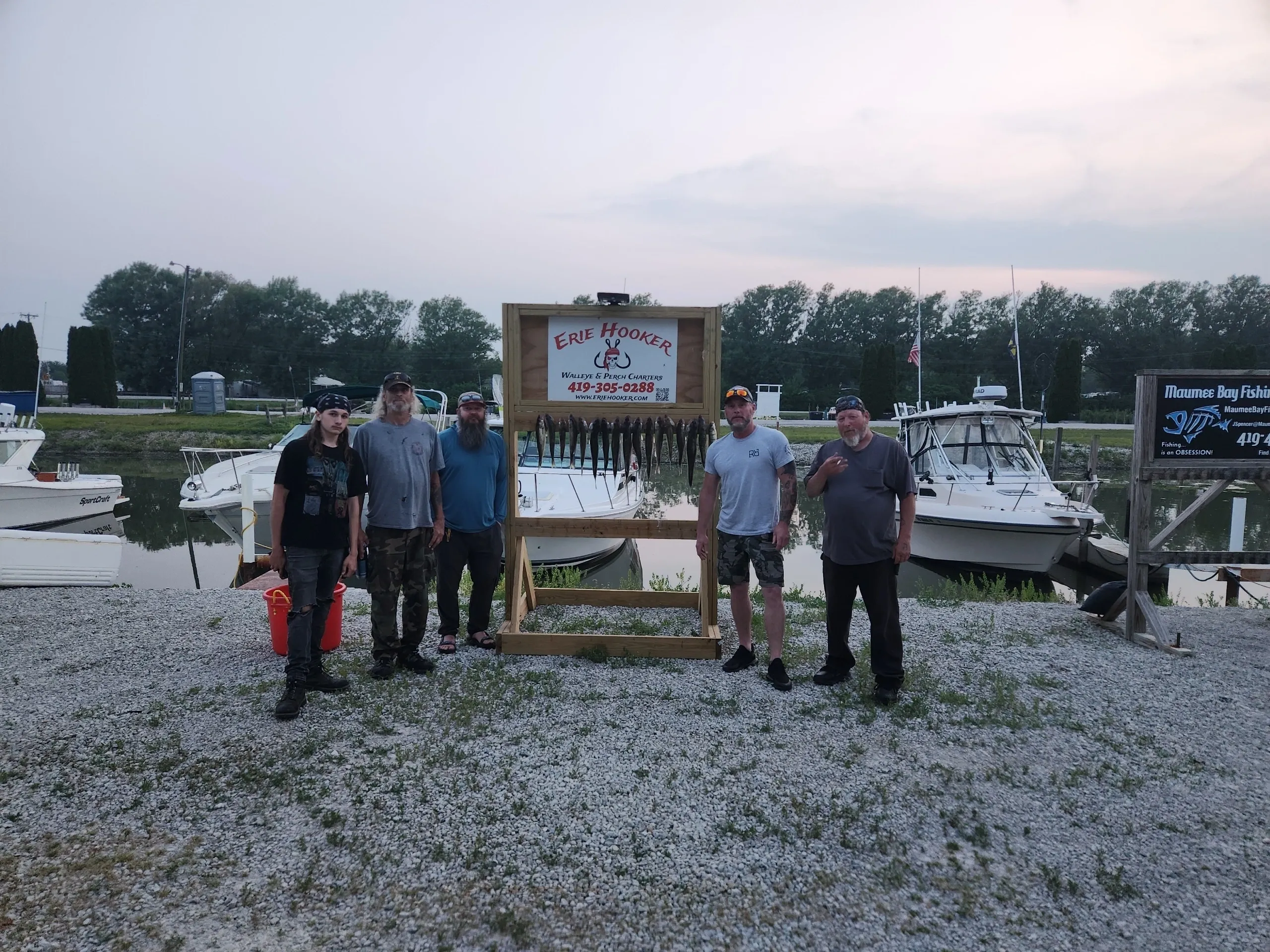 Group of anglers displaying their catch at Erie Hooker charter service in Oak Harbor OH with boats in marina background