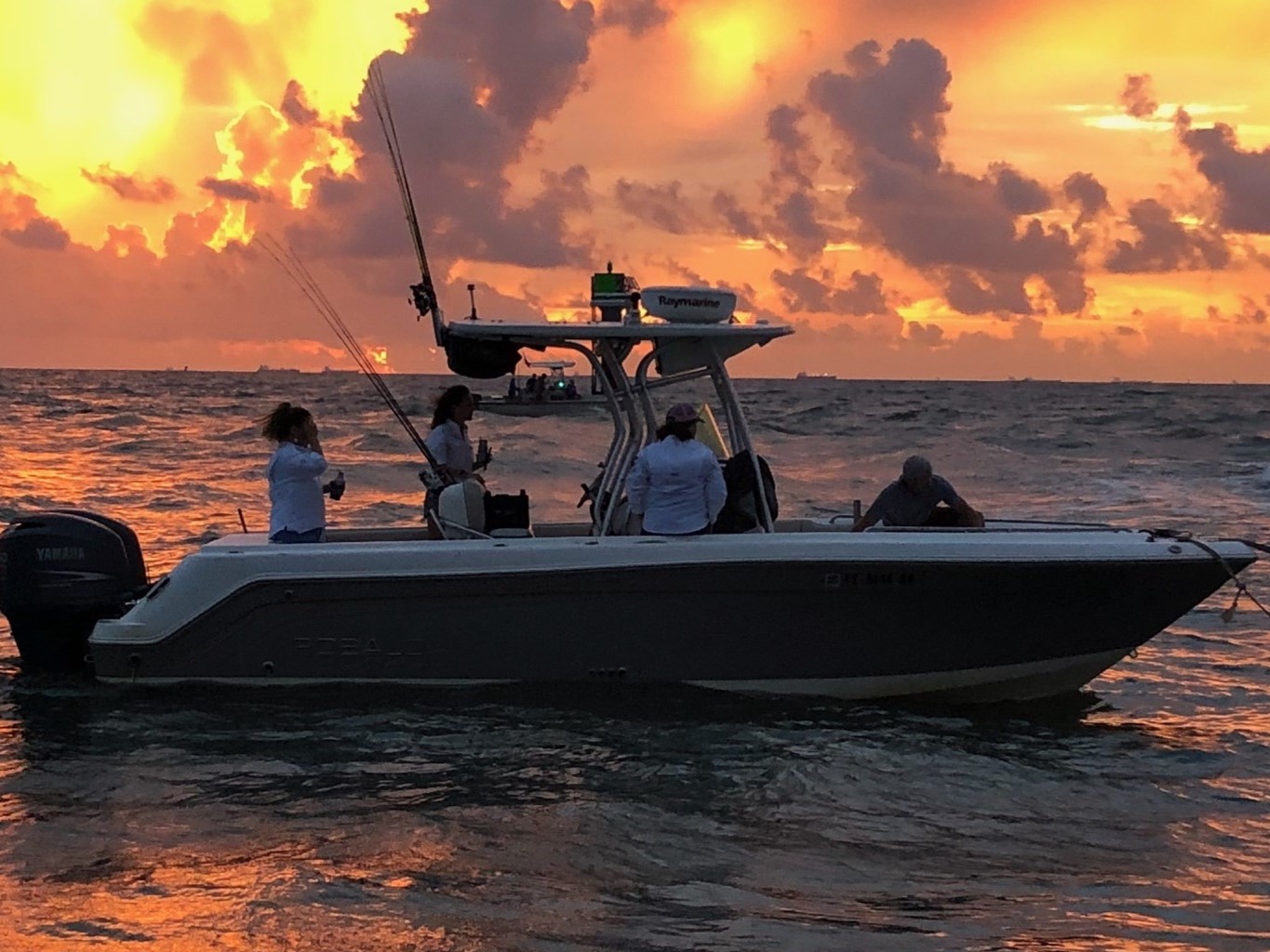 Sunset inshore fishing charter boat on water with golden sky and anglers fishing