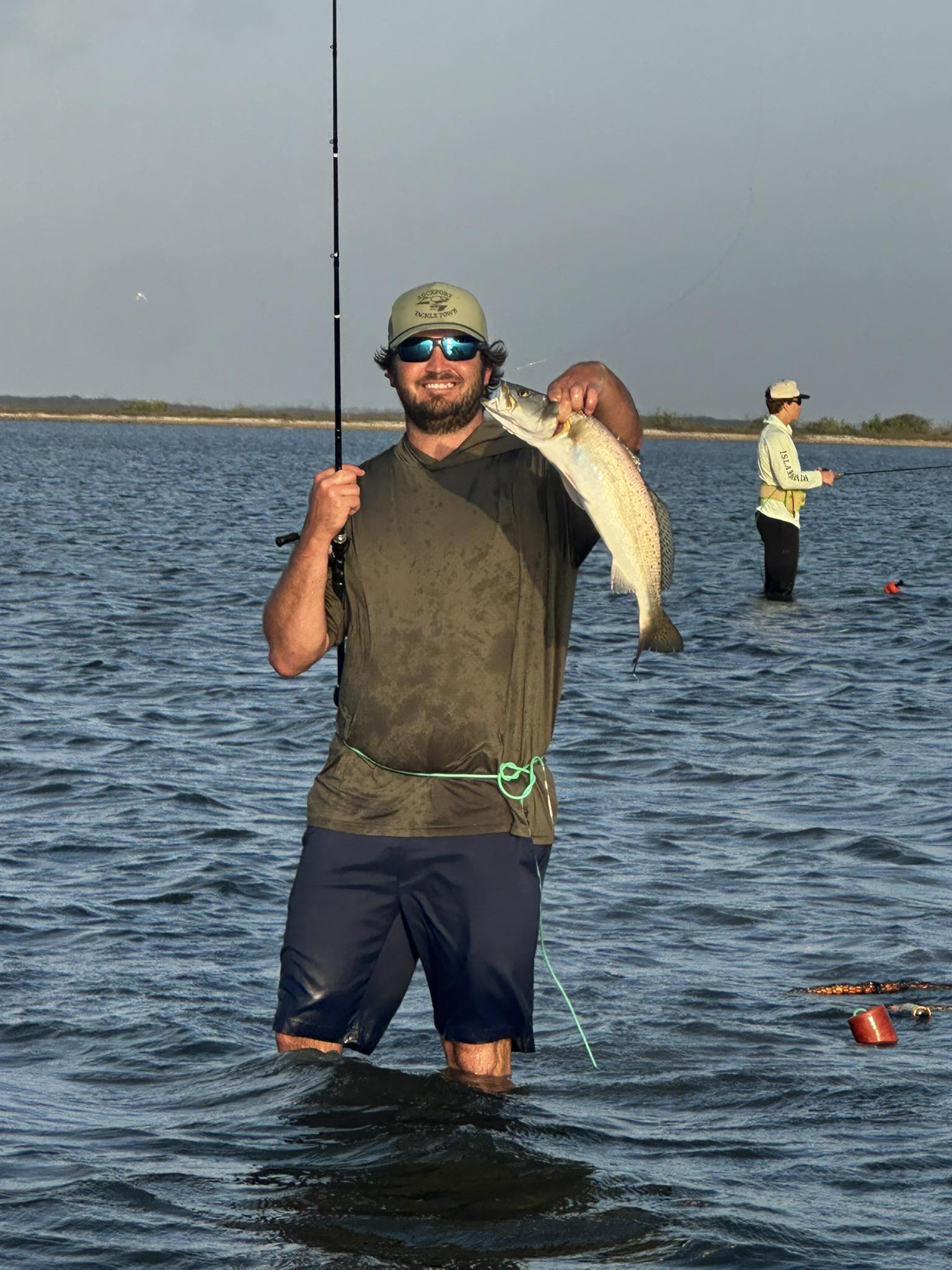 Angler holding caught speckled trout while wade fishing in Rockport TX waters