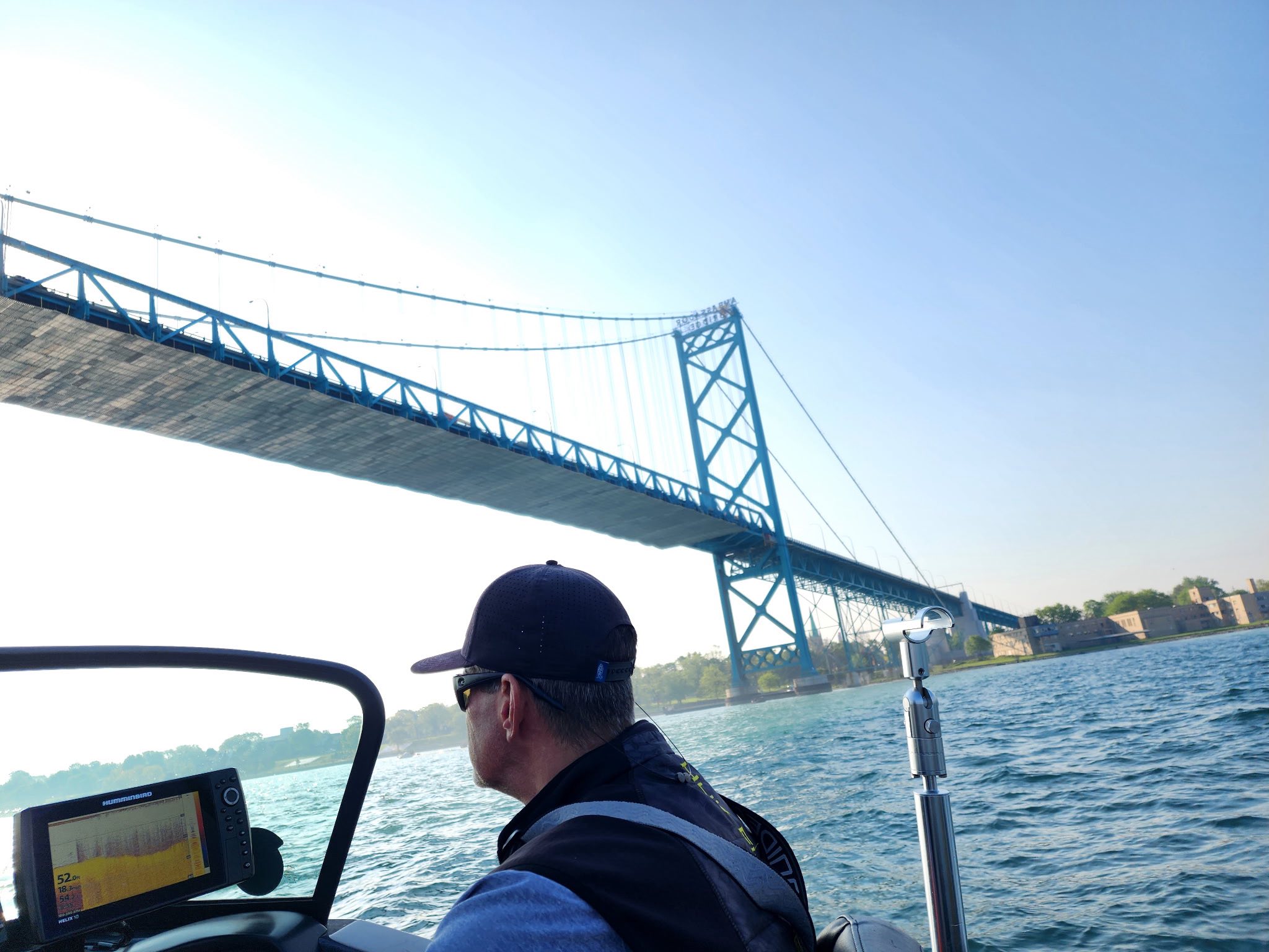 Fishing boat on Detroit River with Ambassador Bridge in background, fish finder display visible