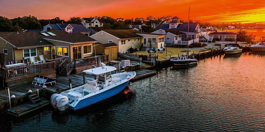 Sunset bay cruise boat on calm Barnegat Light waters with coastal homes and marshes visible