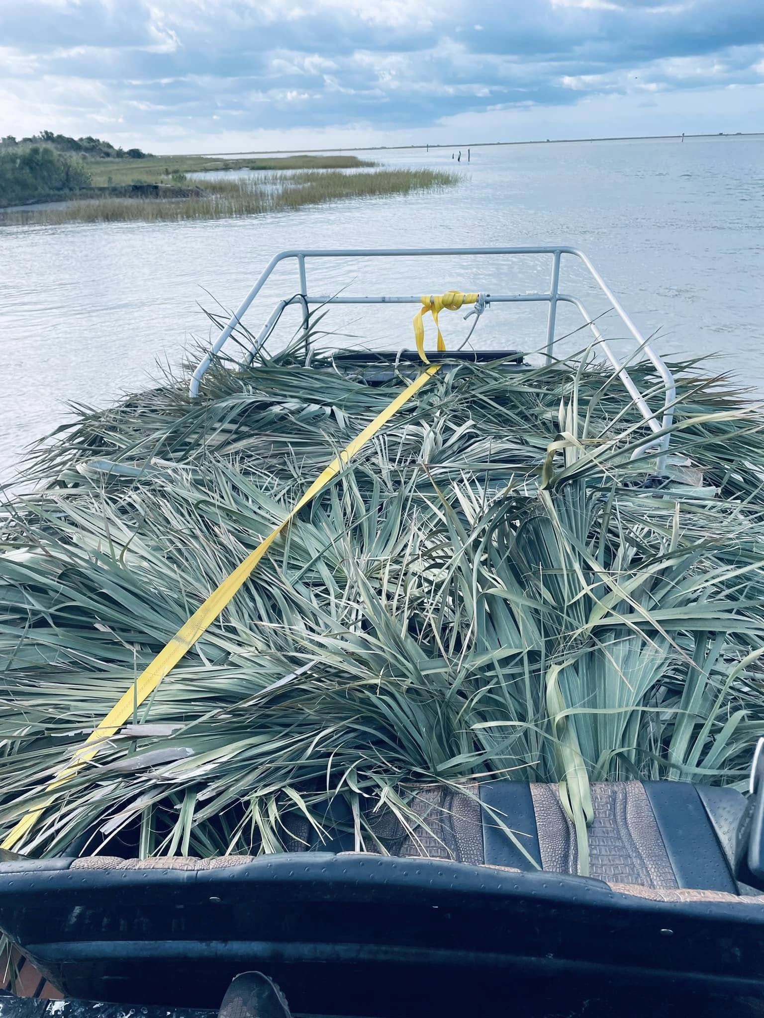 Fishing boat loaded with marsh grass camouflage on calm waters in Port O'Connor TX