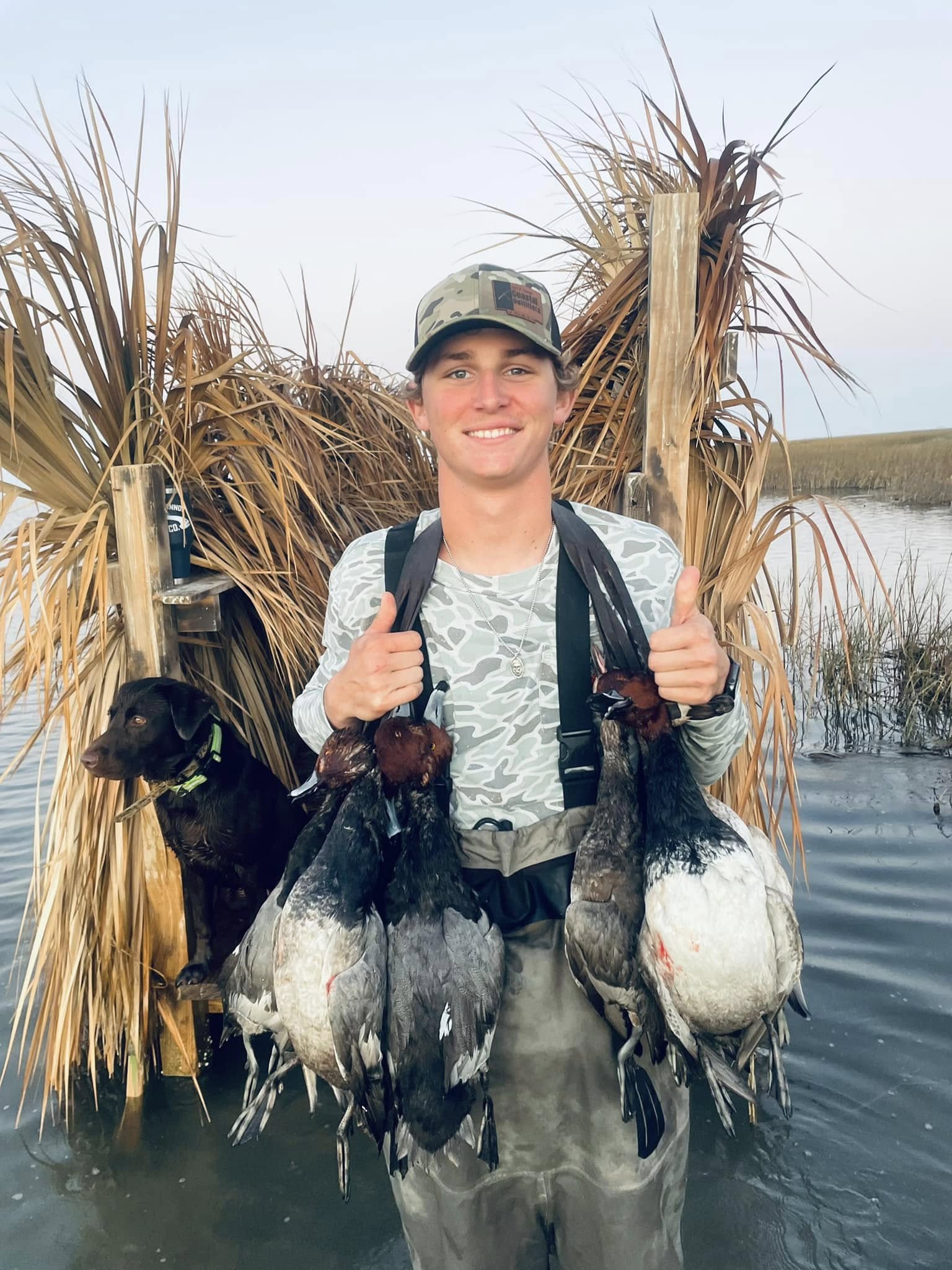 Duck hunting success in Port O'Connor TX with harvested waterfowl and hunting dog in marsh blind