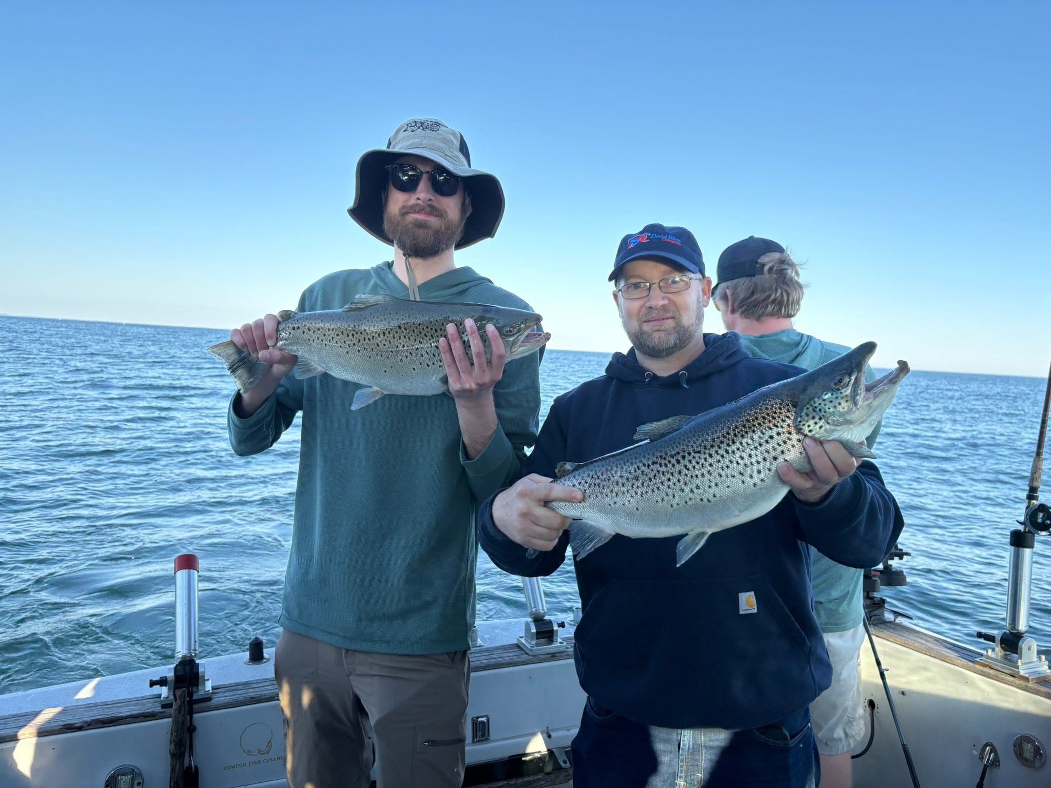 Two anglers displaying fresh caught brown trout on fishing boat in Oswego NY waters