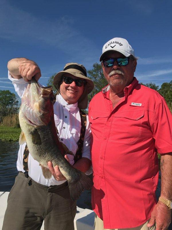 Two anglers displaying a freshly caught bass on a fishing boat in Alba TX