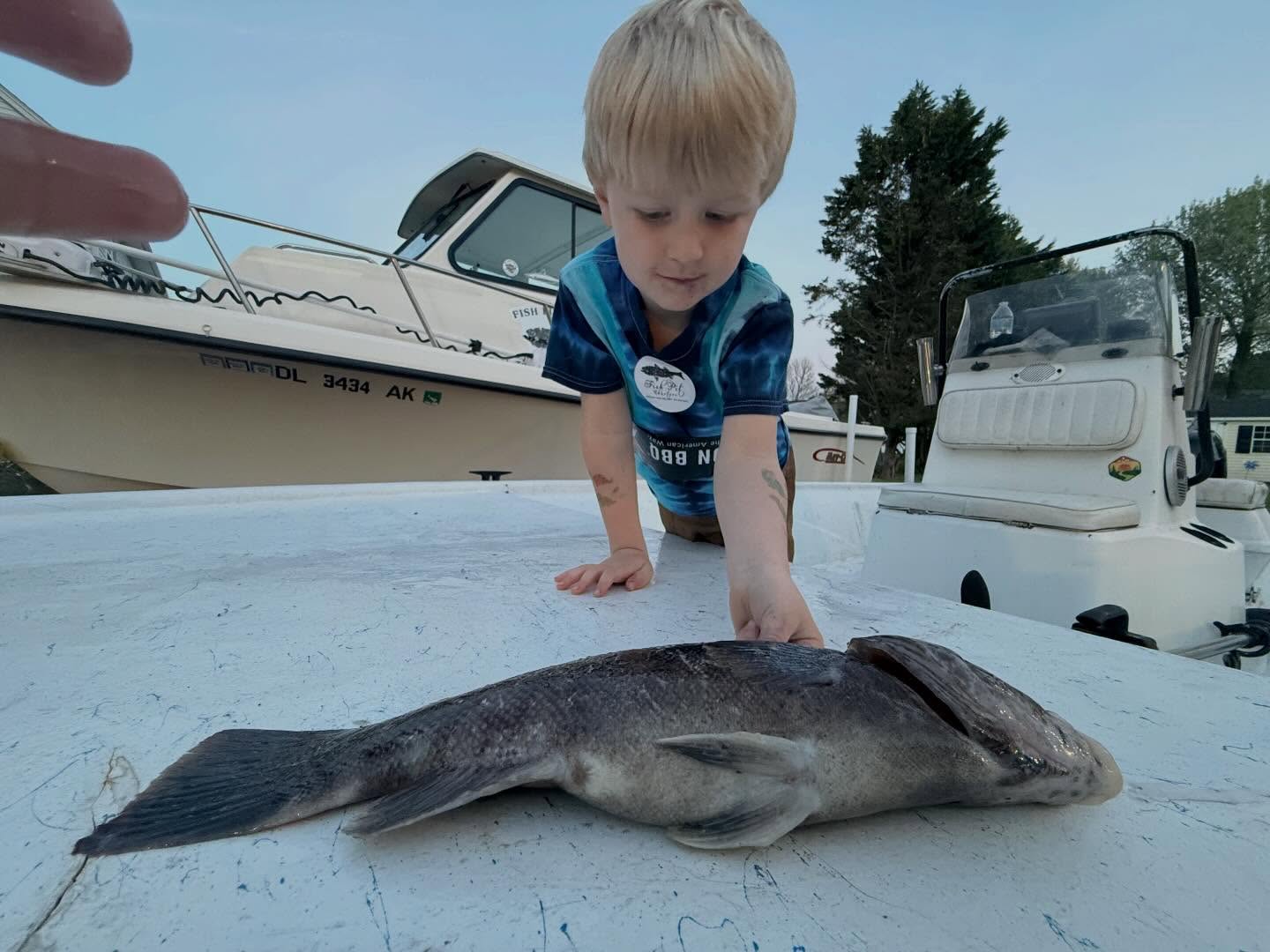 Large flatfish caught during fishing trip in Salisbury MD with young angler examining the catch on boat deck
