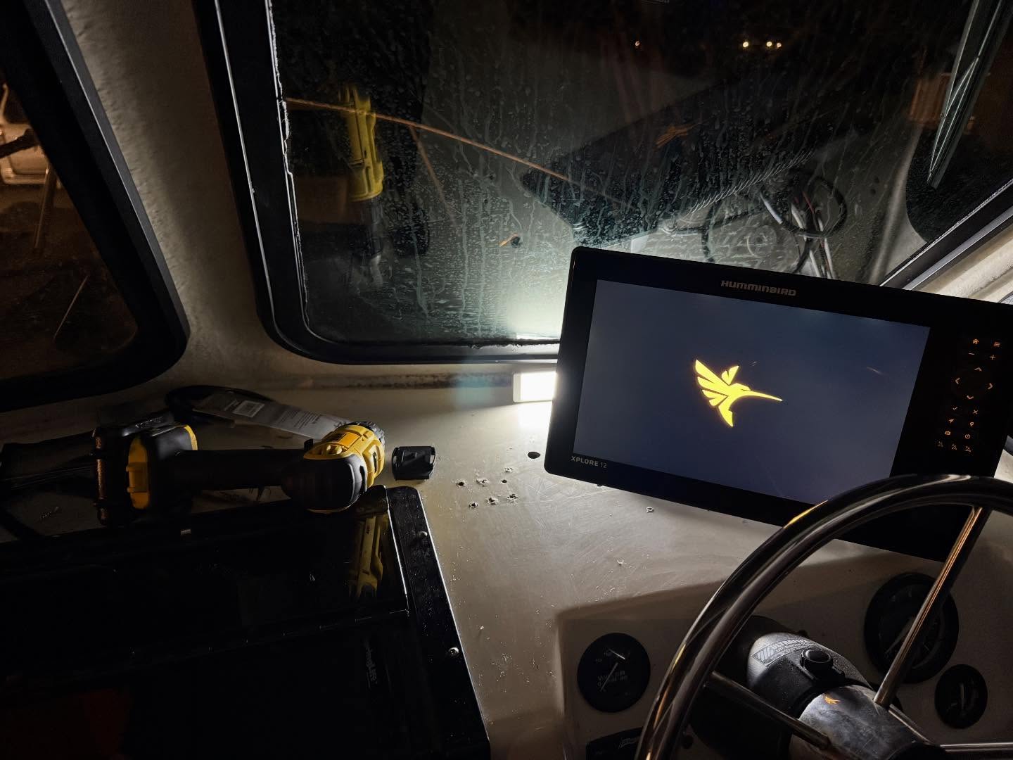 Boat dashboard with fish finder display showing yellow fish logo at night in Salisbury MD