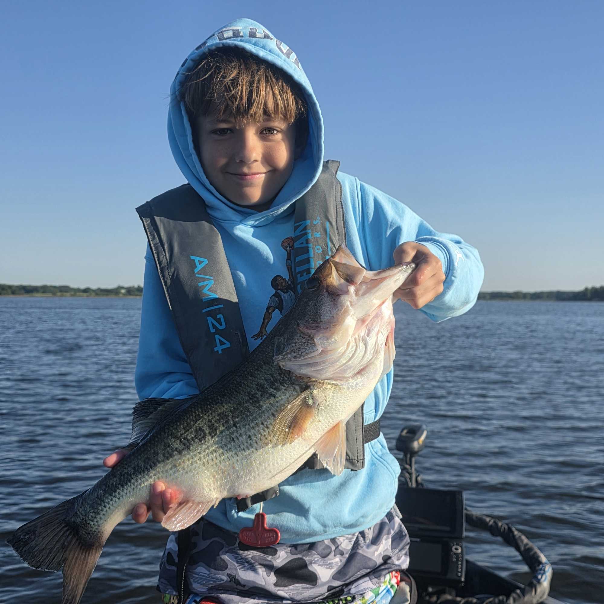 Young angler holding large bass fish on boat in Yantis TX lake