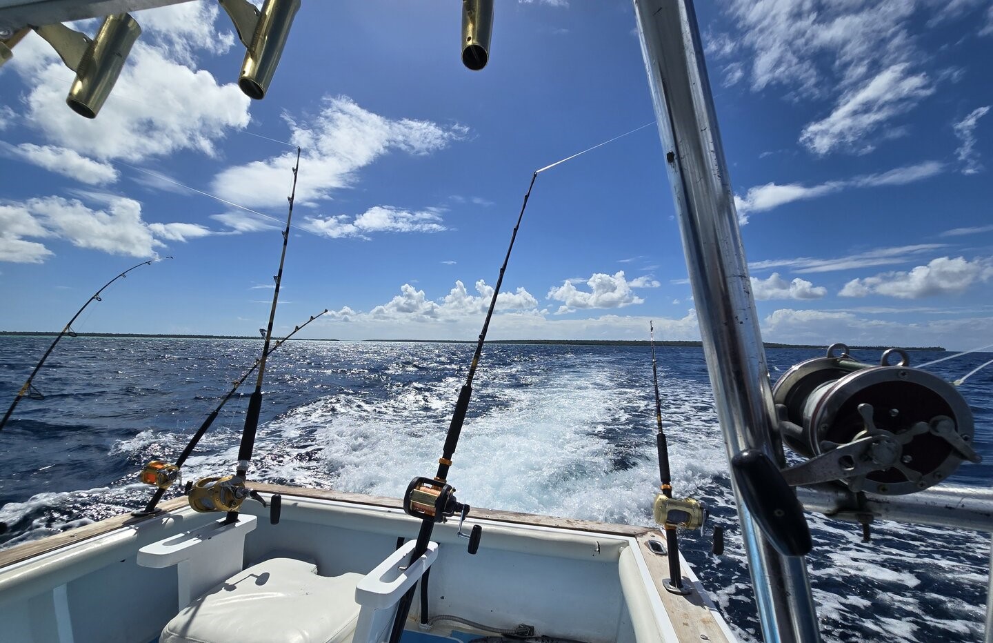 Fishing boat with multiple rods trolling in open ocean waters near Dominicus