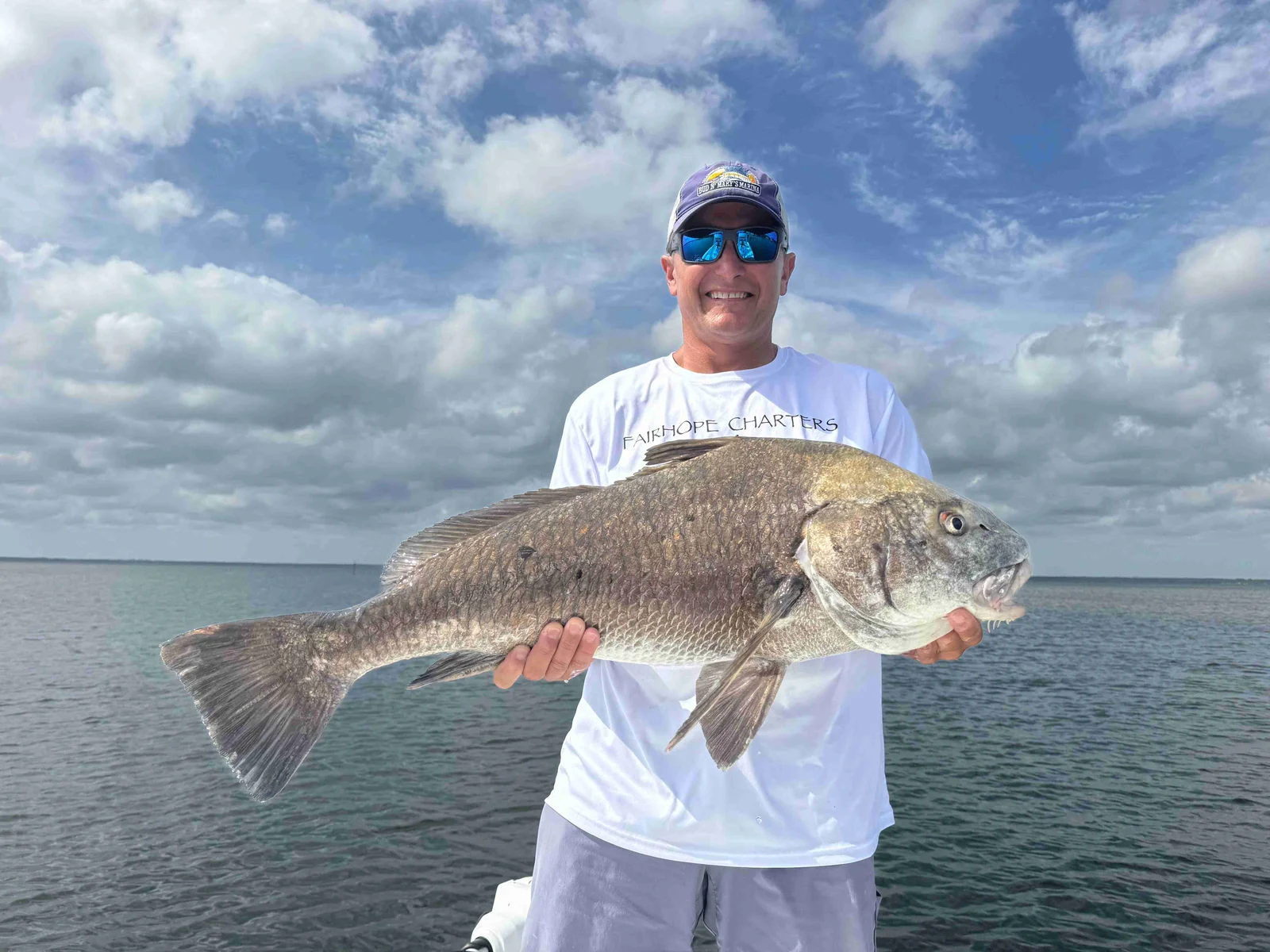 A fisherman holding a black drum fish in Fairhope