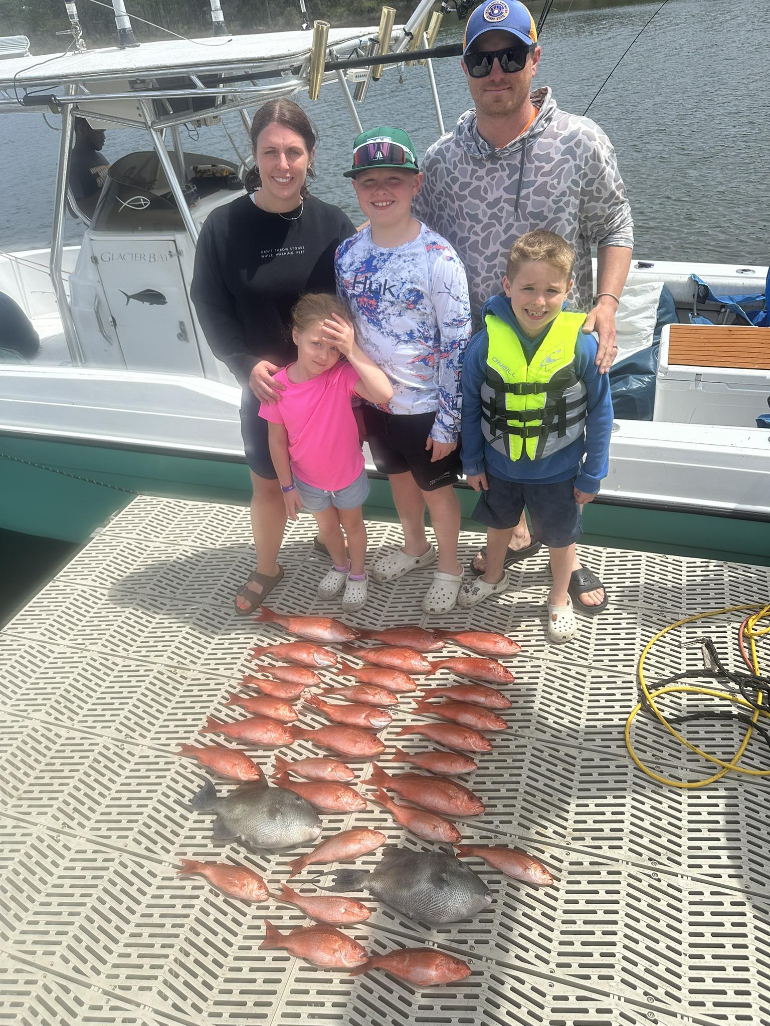 Family fishing trip with large catch of red snapper laid out on boat deck in Pensacola FL