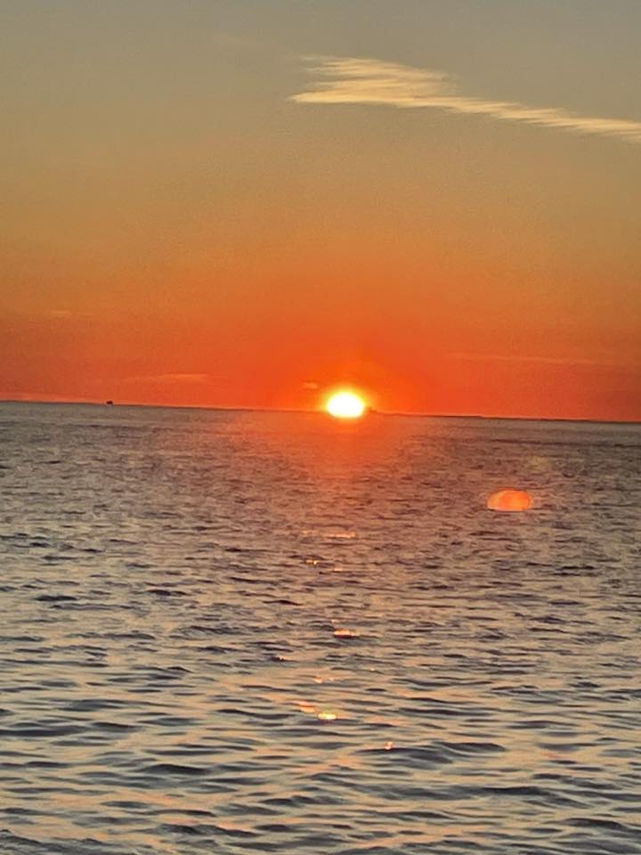Sunset over calm ocean waters in Olcott NY with orange and golden sky