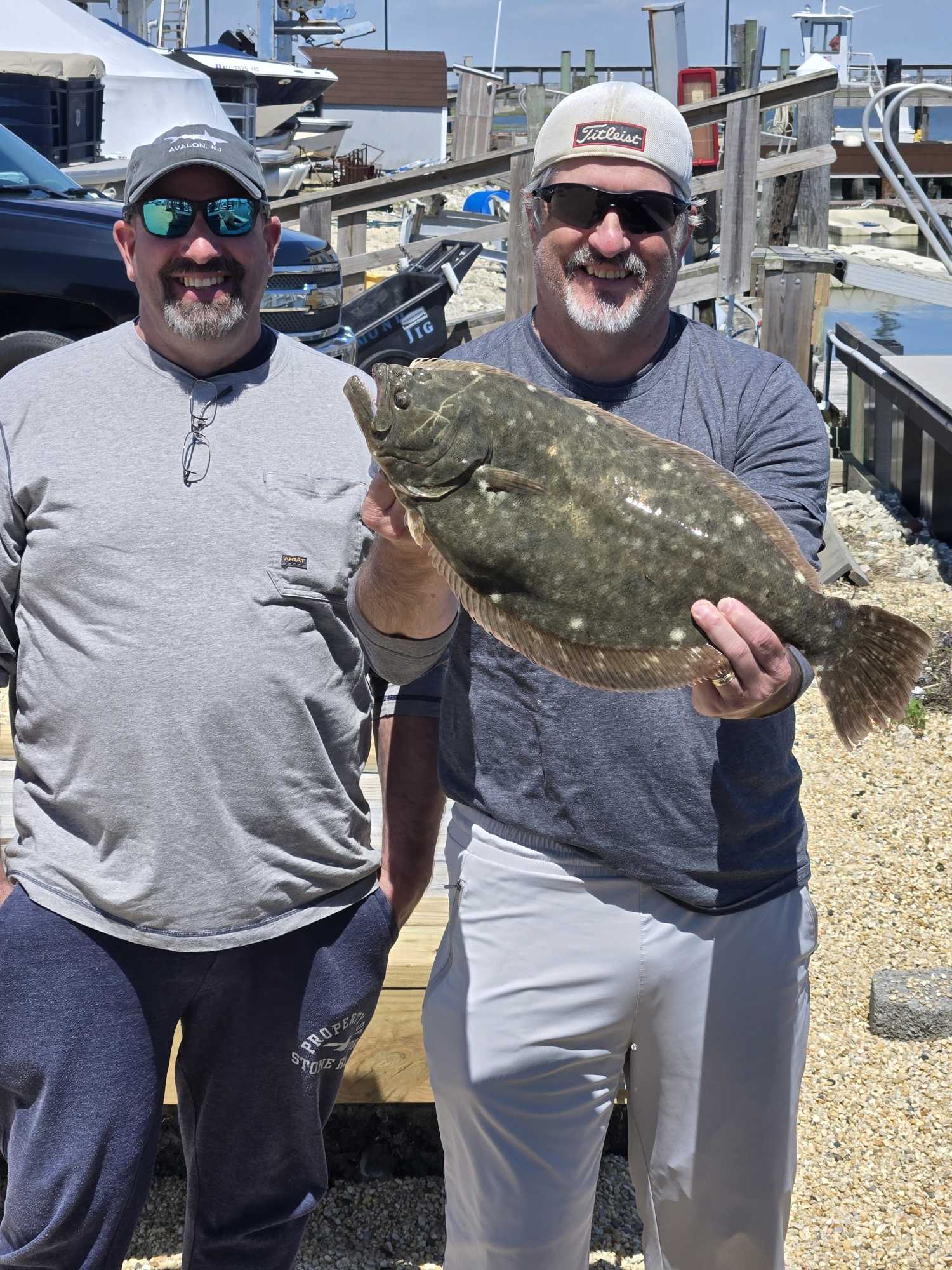 Two anglers holding large summer flounder catch at Avalon NJ marina dock