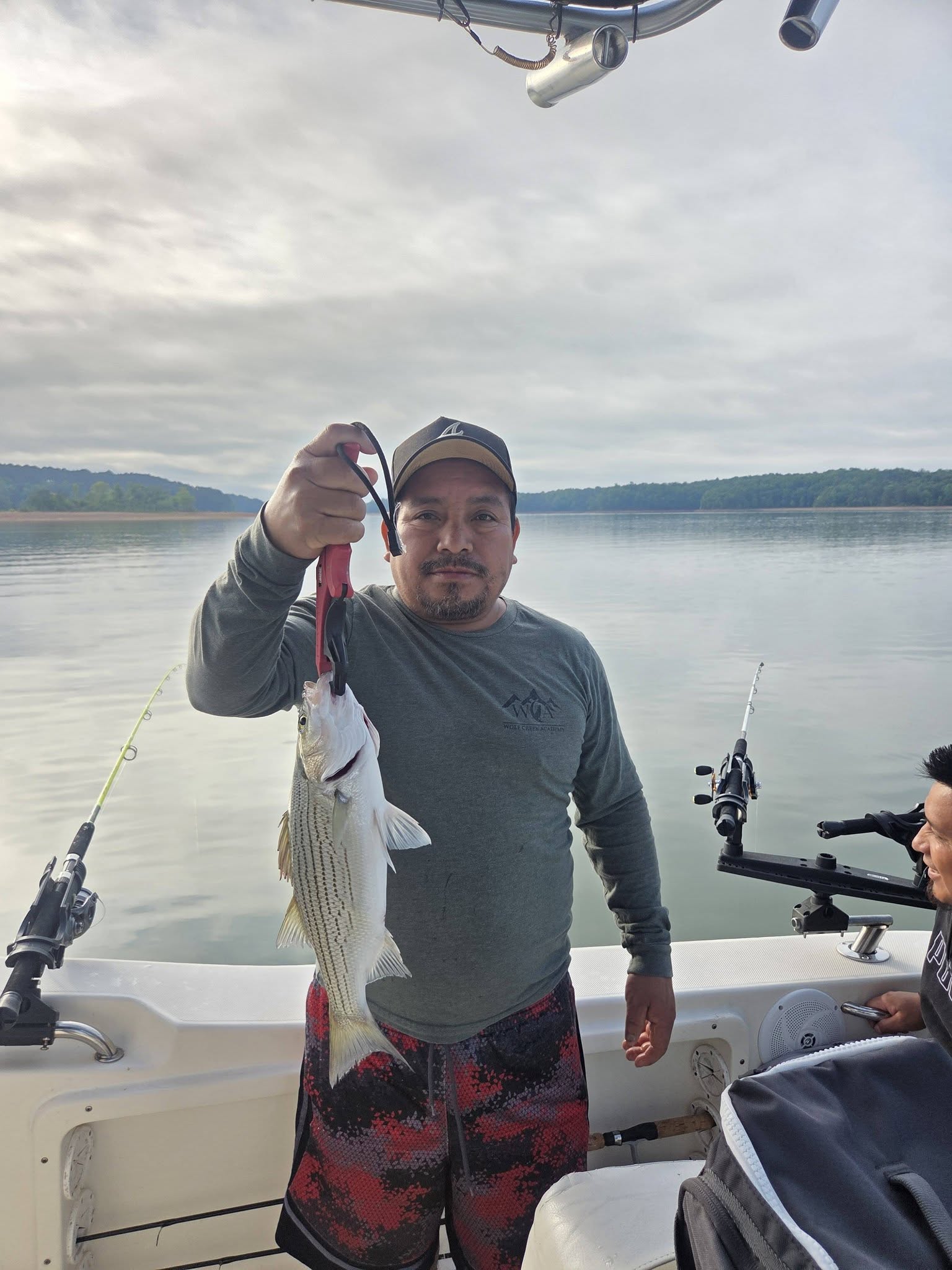 Angler holding striped bass catch on fishing boat in Lyman SC