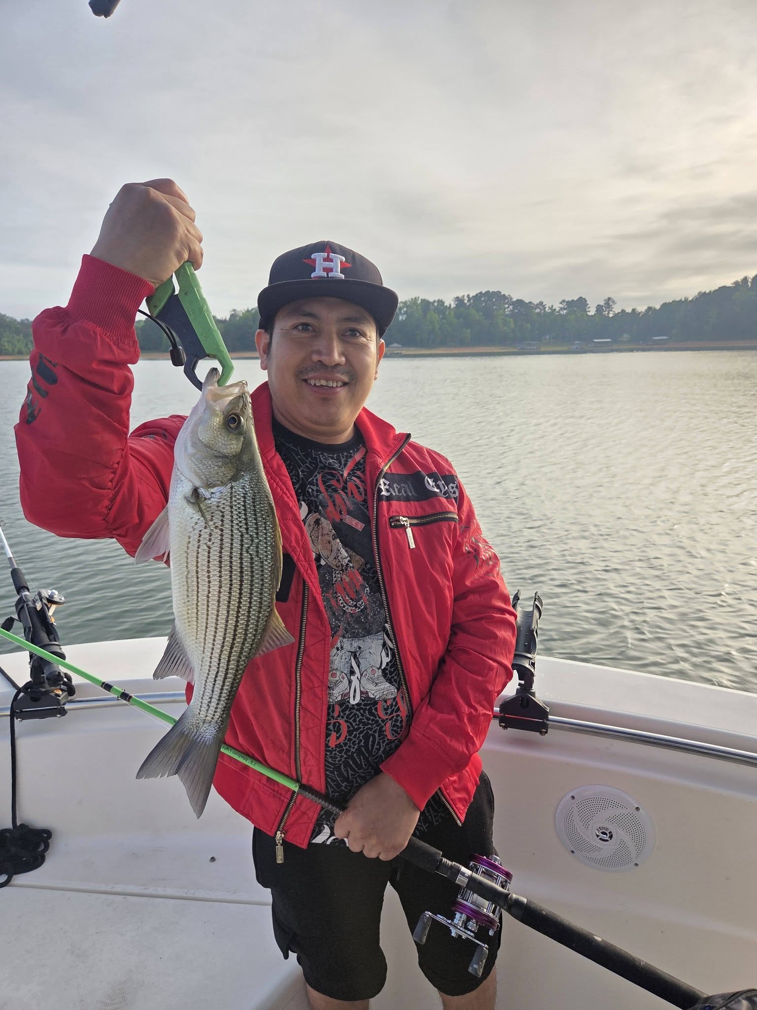 Angler holding freshly caught striped bass on fishing boat in Lyman SC