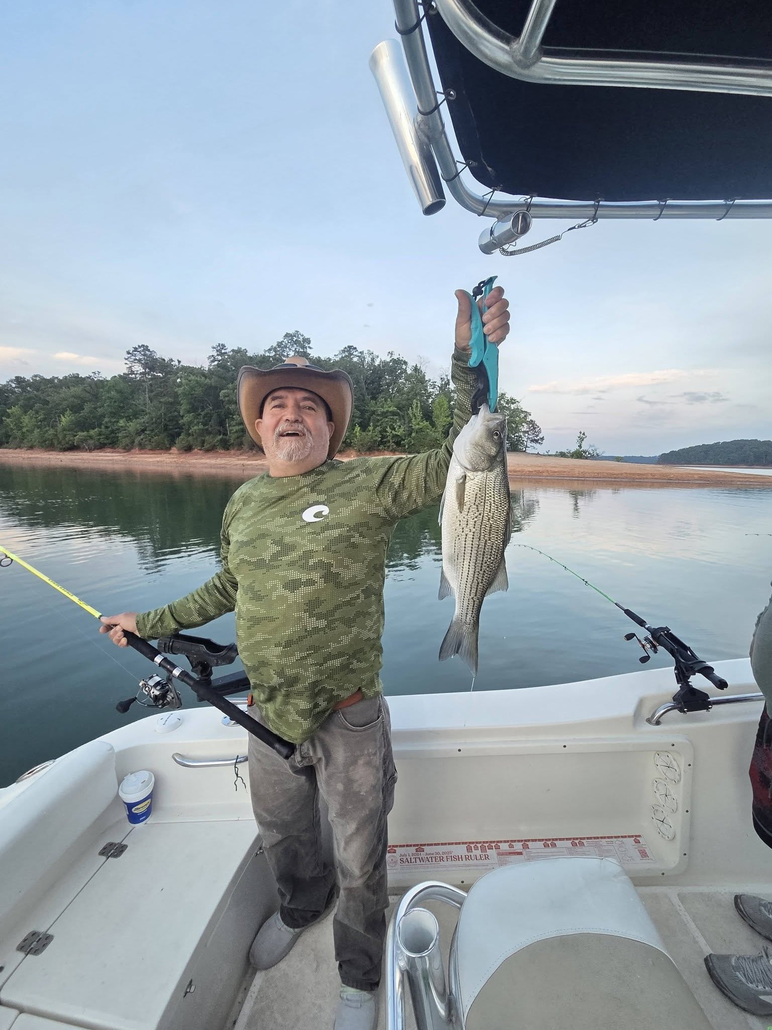 Angler holding striped bass fish on boat in Lyman SC lake