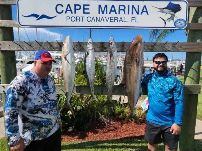 Two anglers with a pair of large fish in front of the Cape Canaveral lighthouse