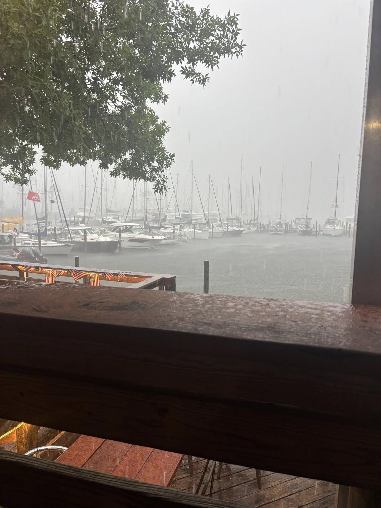 Heavy rain falls over marina with sailboats and fishing boats docked in Niceville FL during storm