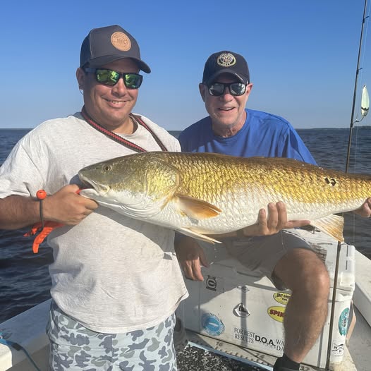 Two anglers displaying a large redfish caught during fishing trip in Greenville NC