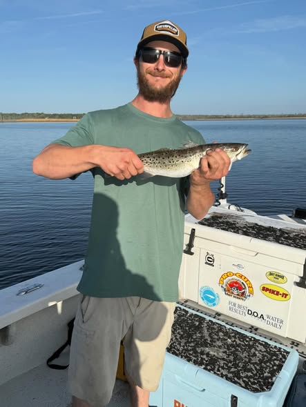 Angler displaying caught speckled trout on fishing boat in Greenville NC waters