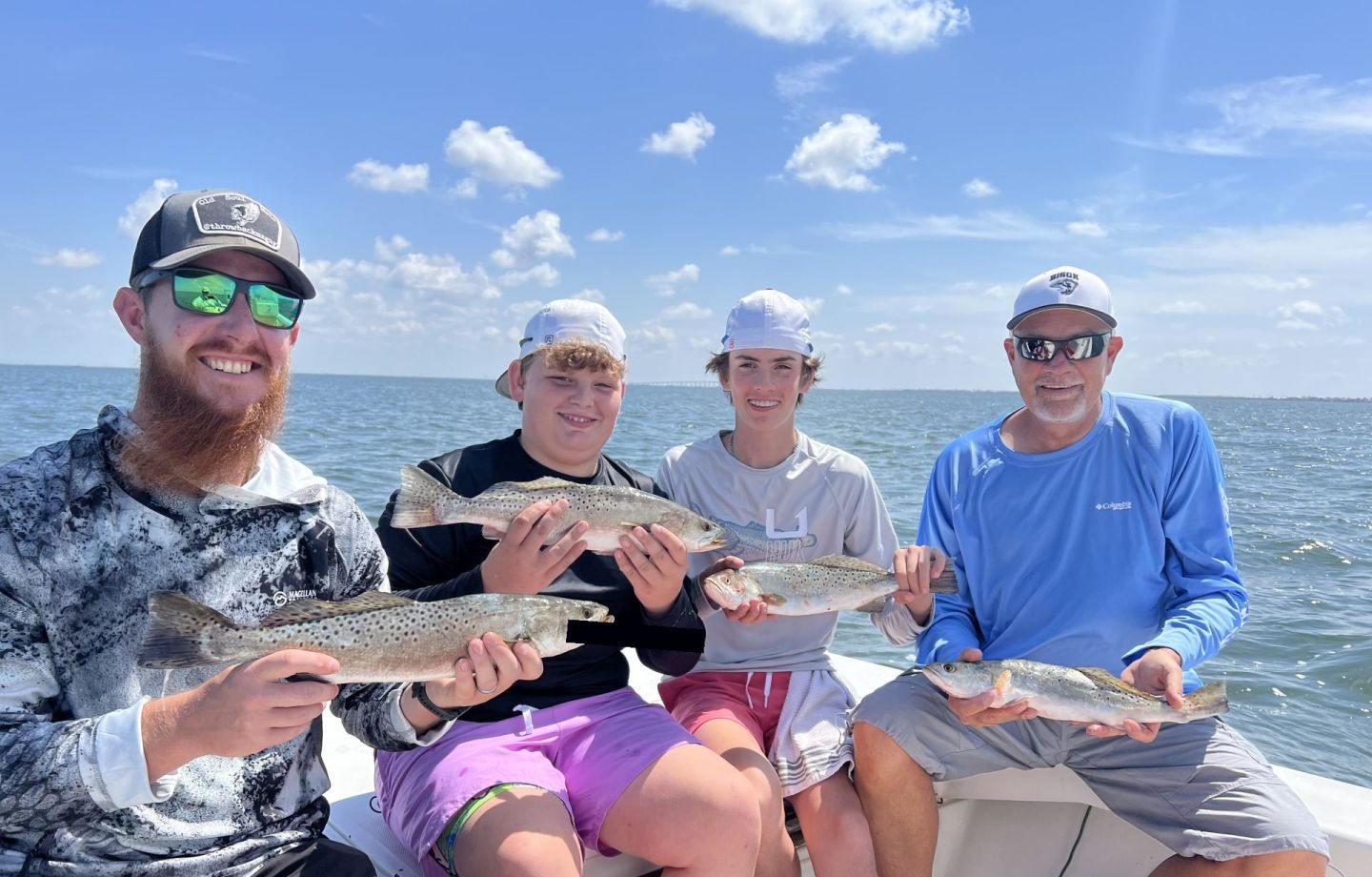 Four anglers displaying speckled trout catch on fishing boat in Corpus Christi TX waters