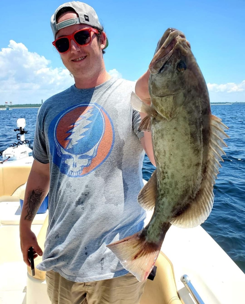 A fisherman holding a large gag grouper fish in Pensacola