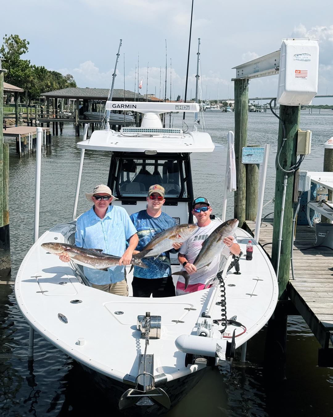 Three anglers displaying freshly caught cobia and greater amberjack on fishing boat docked at Port Orange FL marina