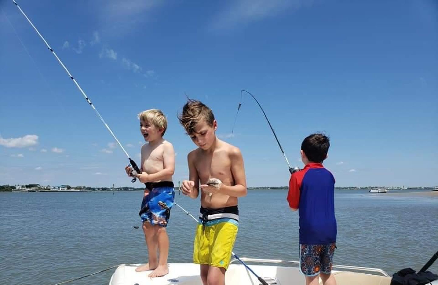 Three young anglers fishing from boat deck in St. Augustine FL waters with fishing rods